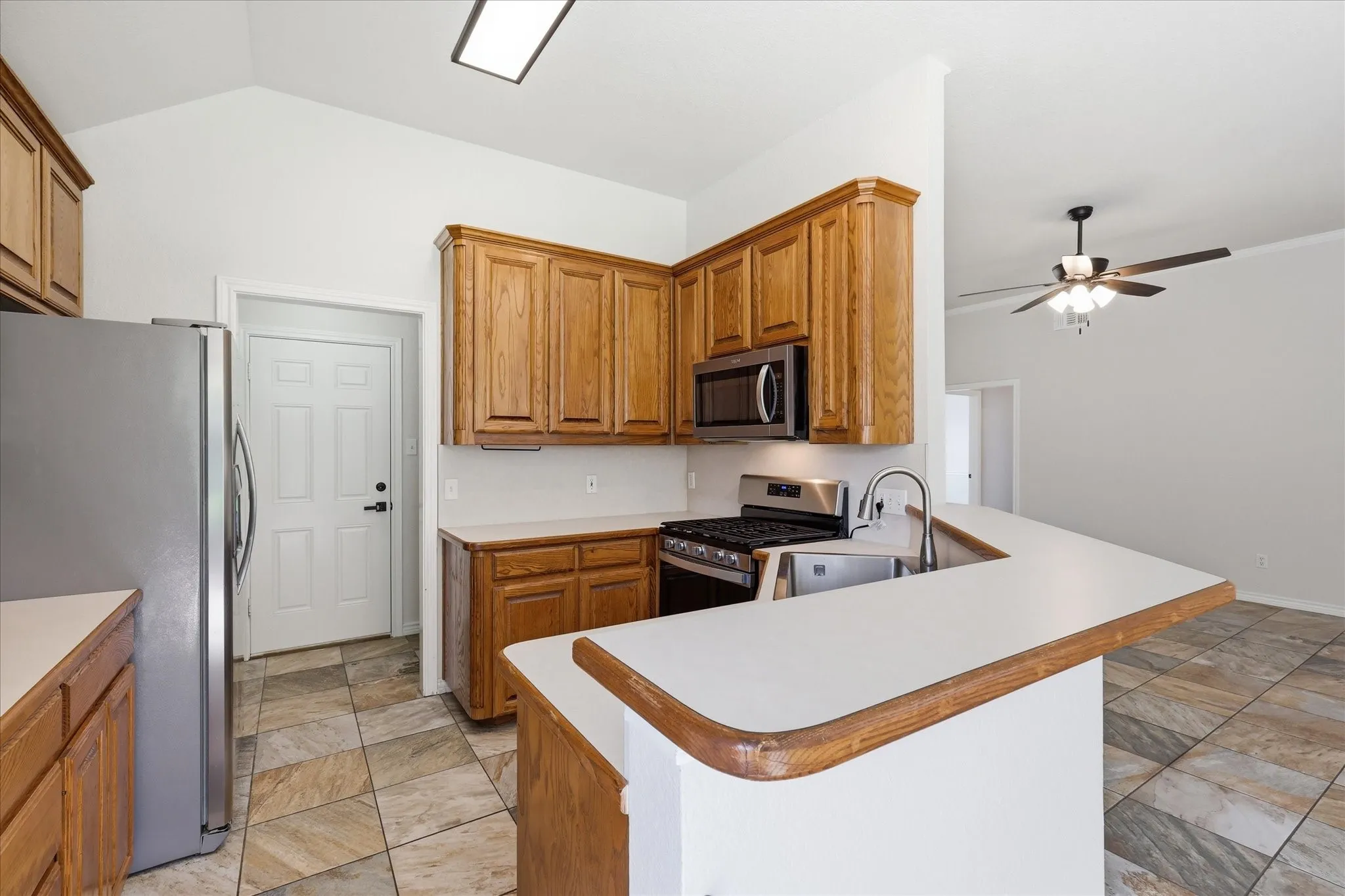 Kitchen featuring wood cabinetry, stainless steel appliances, a bar-height countertop, and tile flooring