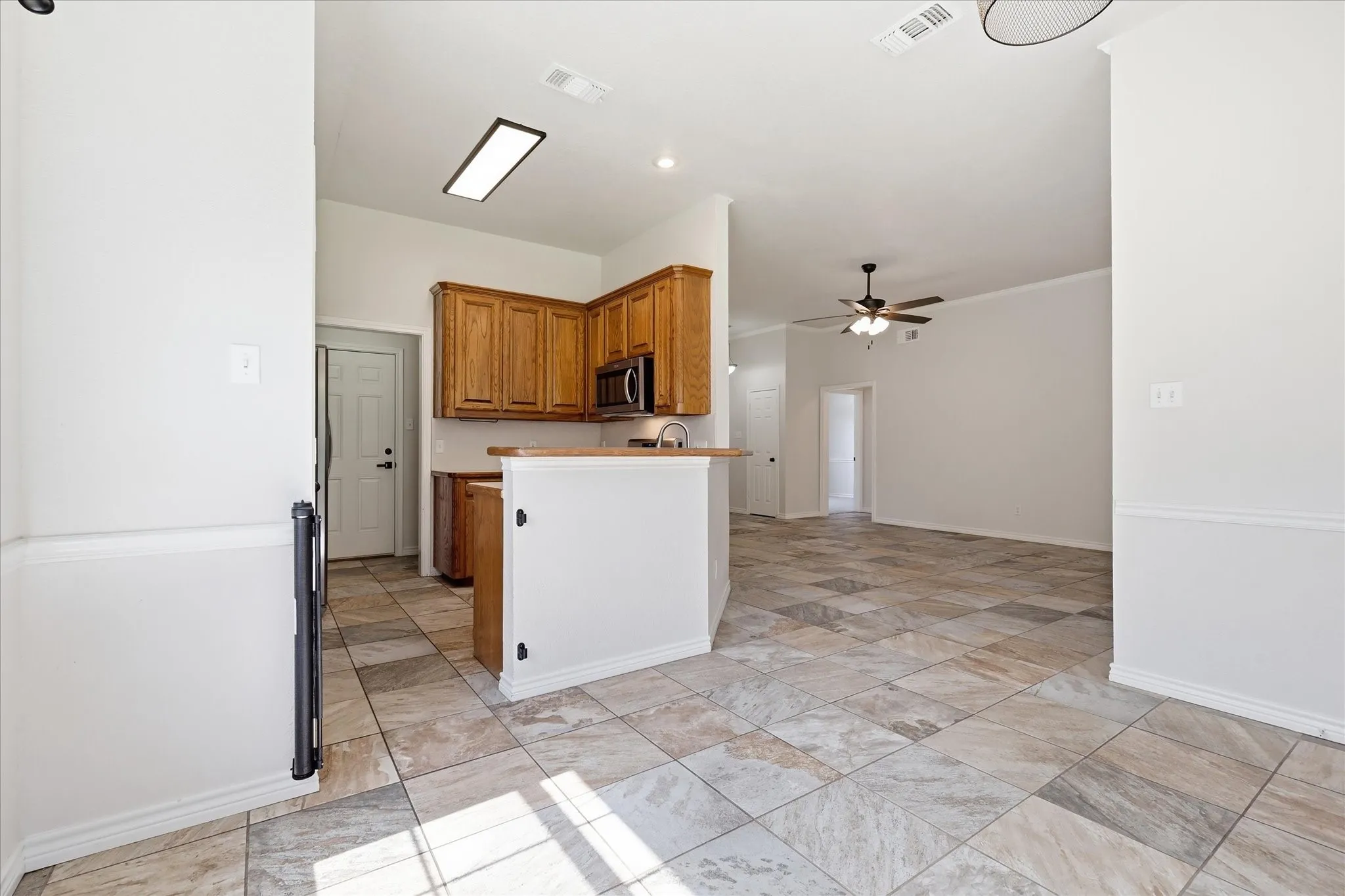 Kitchen featuring rich wood cabinetry, stainless steel microwave, and multi-toned tile flooring