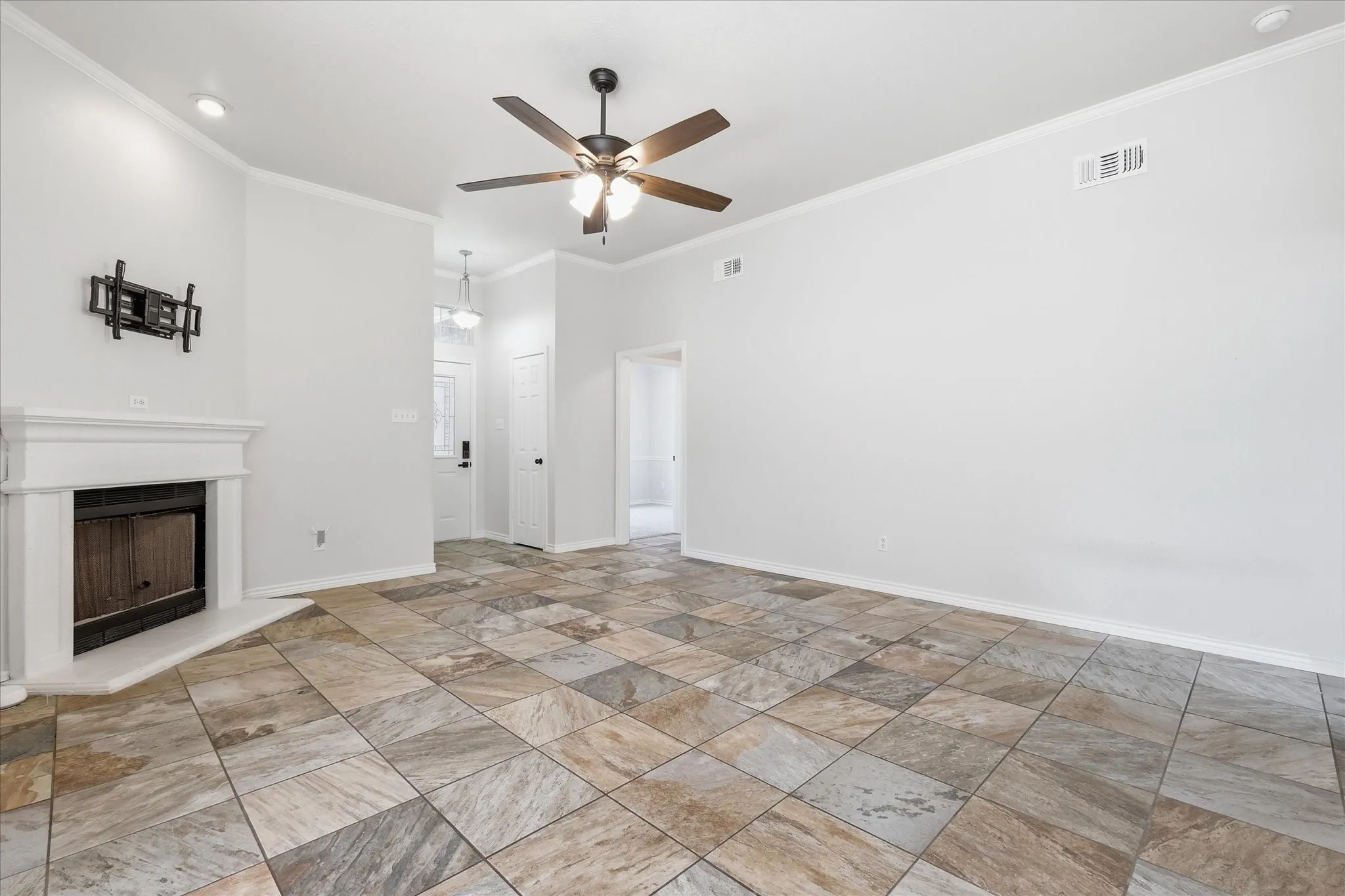 Spacious living area featuring variegated tile flooring and a white mantel fireplace with a metal firebox