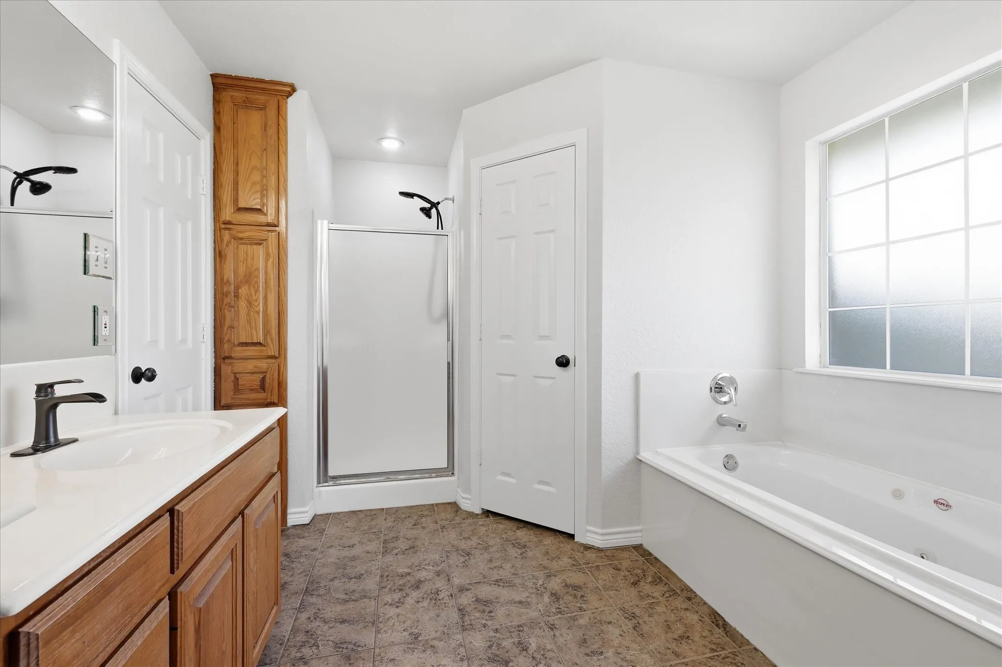 Bathroom featuring a deep soaking tub, a separate shower with a glass enclosure, and a vanity with a single basin