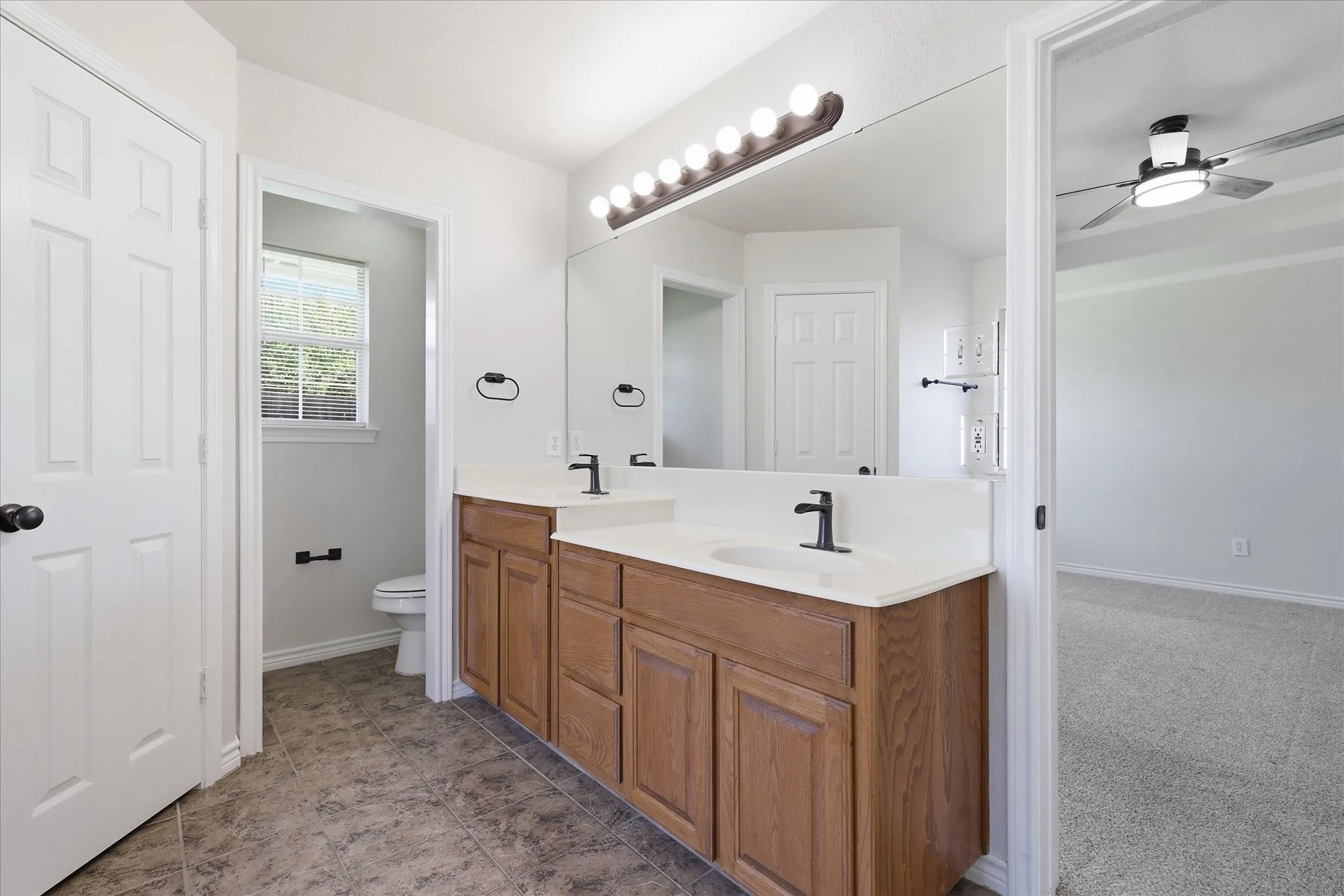Double vanity with light wood-finish cabinetry and white countertops
