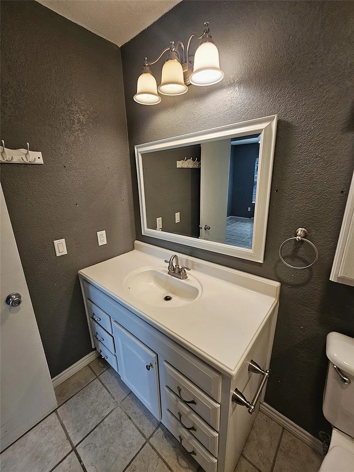 Bathroom vanity featuring a white countertop with an integrated sink, brushed nickel faucet, and a wall-mounted mirror with a white frame