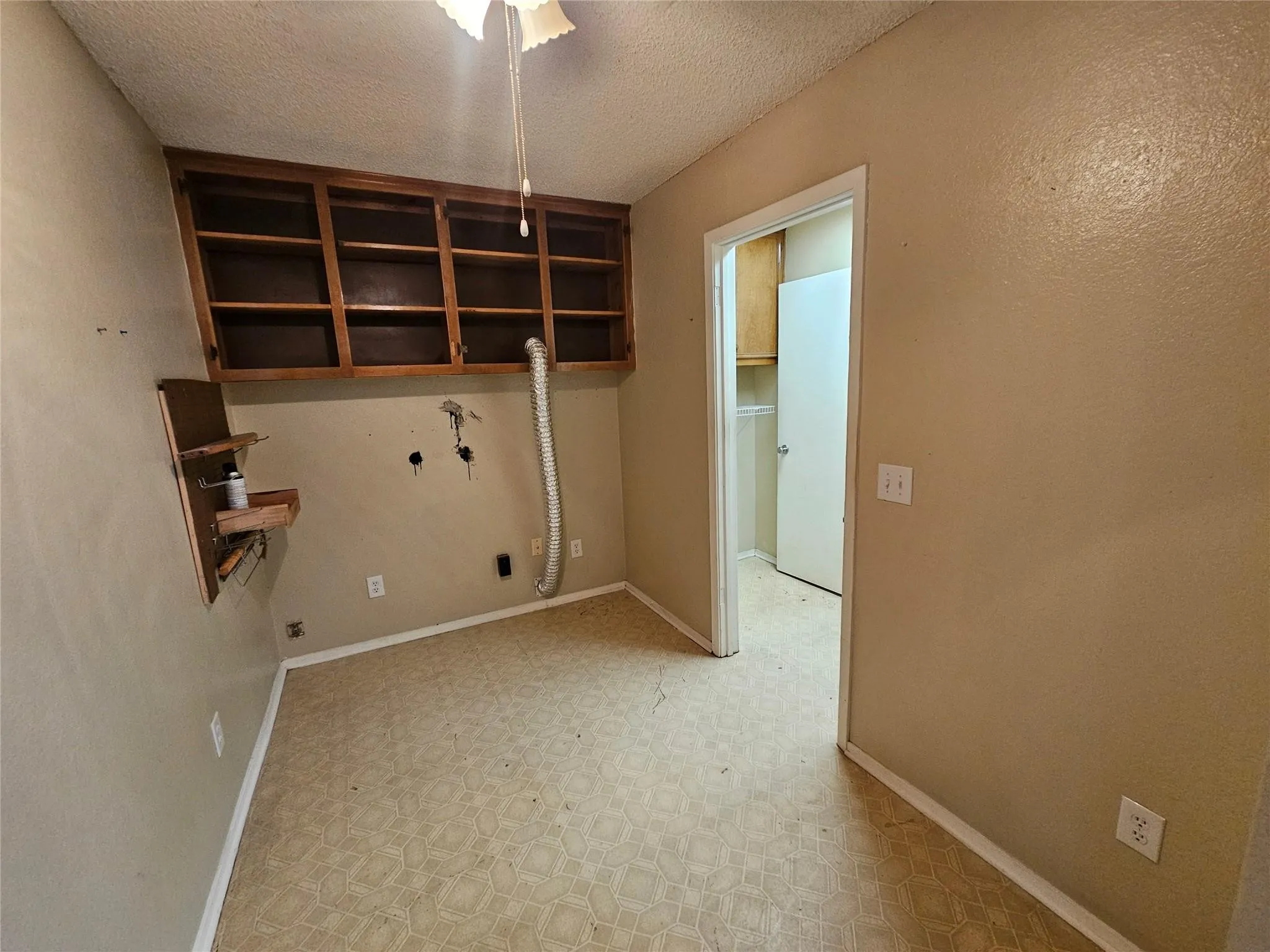 Utility space featuring built-in wood cabinetry, patterned flooring, and a ceiling-mounted light fixture