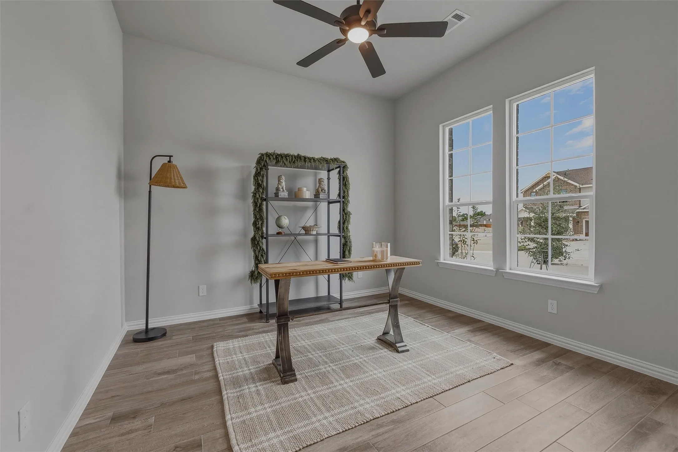 Vaulted ceiling with a ceiling fan, dual large windows, and wood-finish flooring