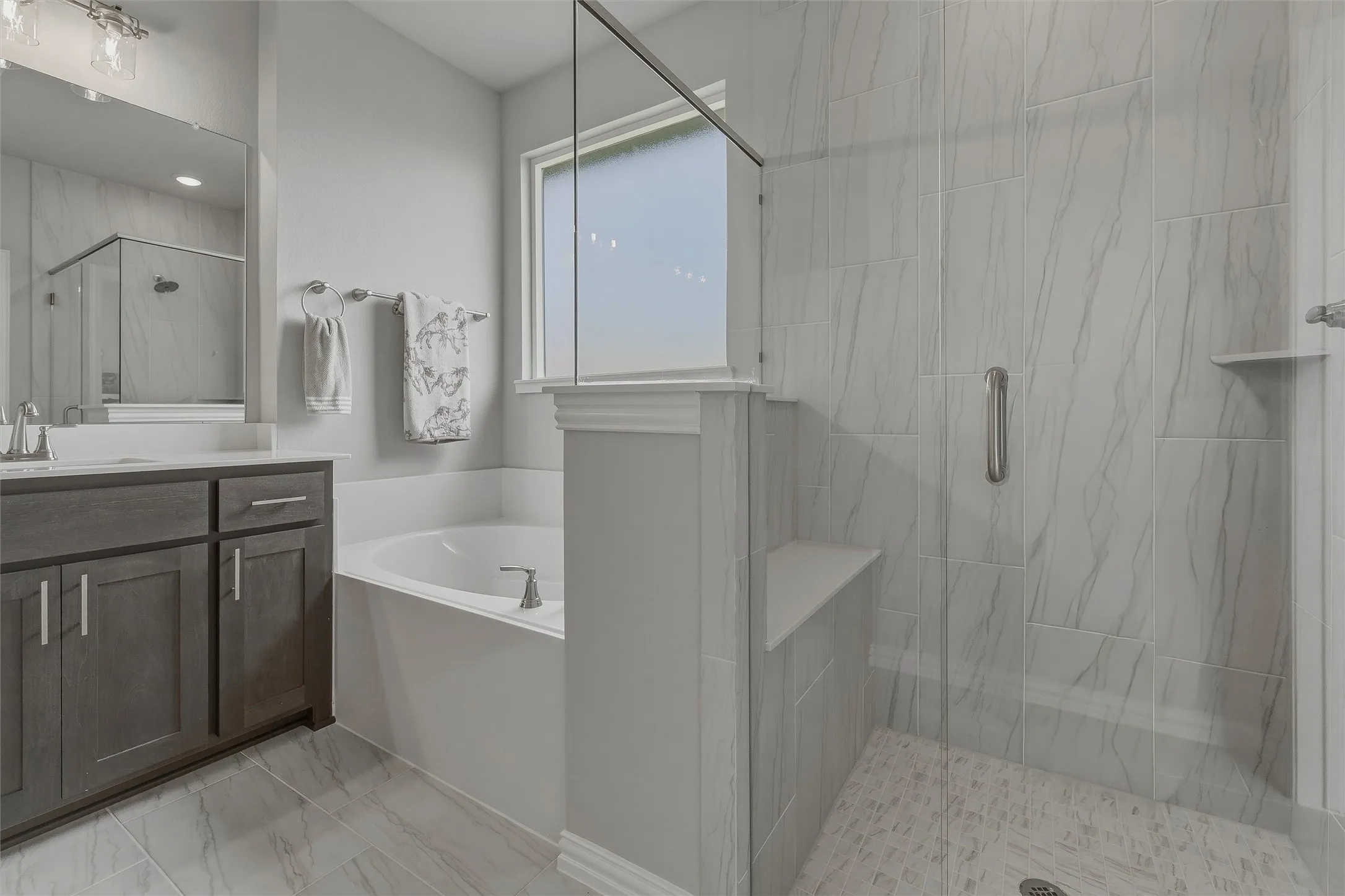 Spacious bathroom featuring a built-in soaking tub, separate glass-enclosed shower with a bench, and a vanity with dark wood-finish cabinetry