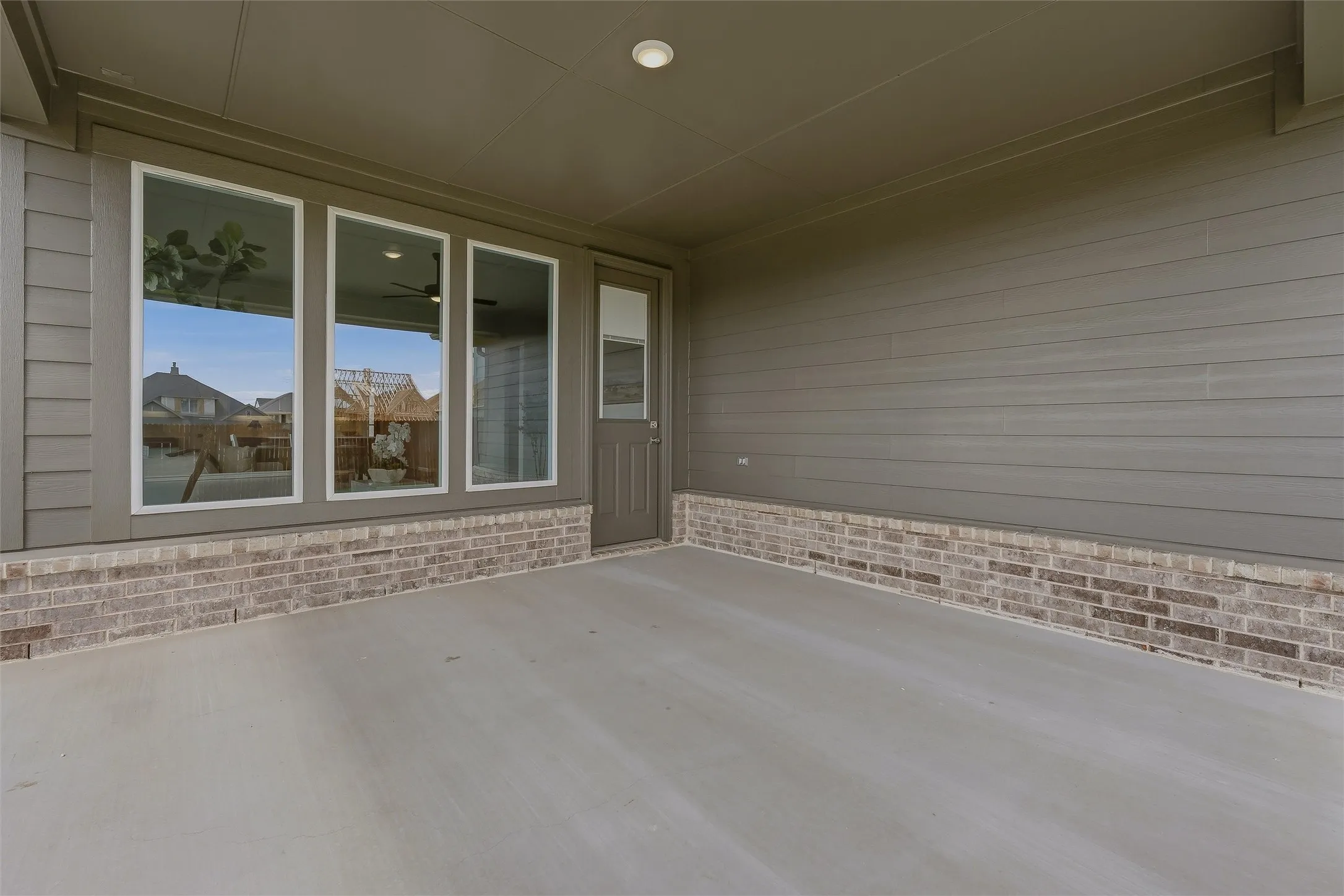 Covered patio with a concrete surface, brick base, and multiple windows