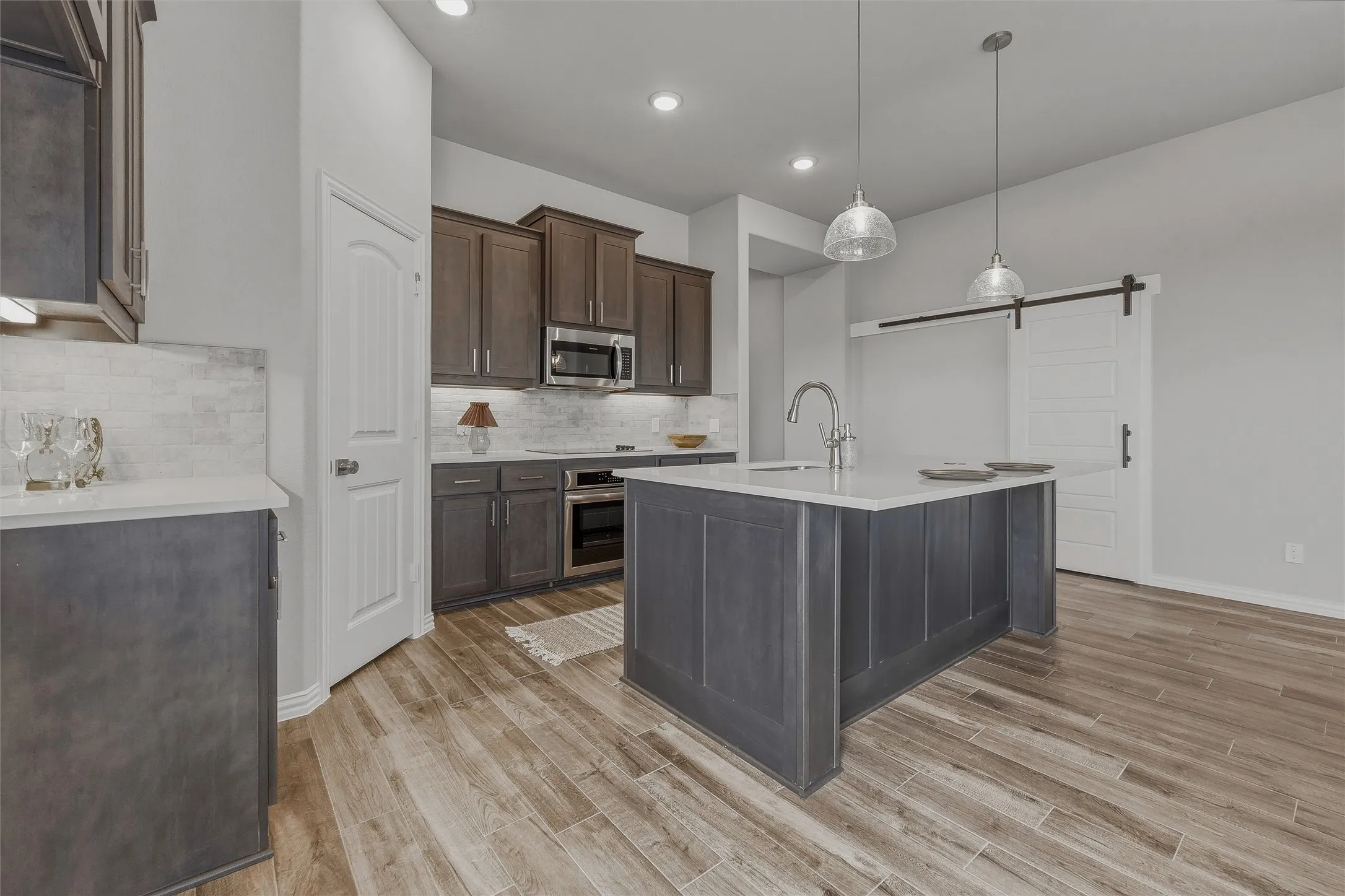 Gourmet kitchen featuring a central island, recessed lighting, wood-finish flooring, subway tile backsplash, and stainless steel appliances