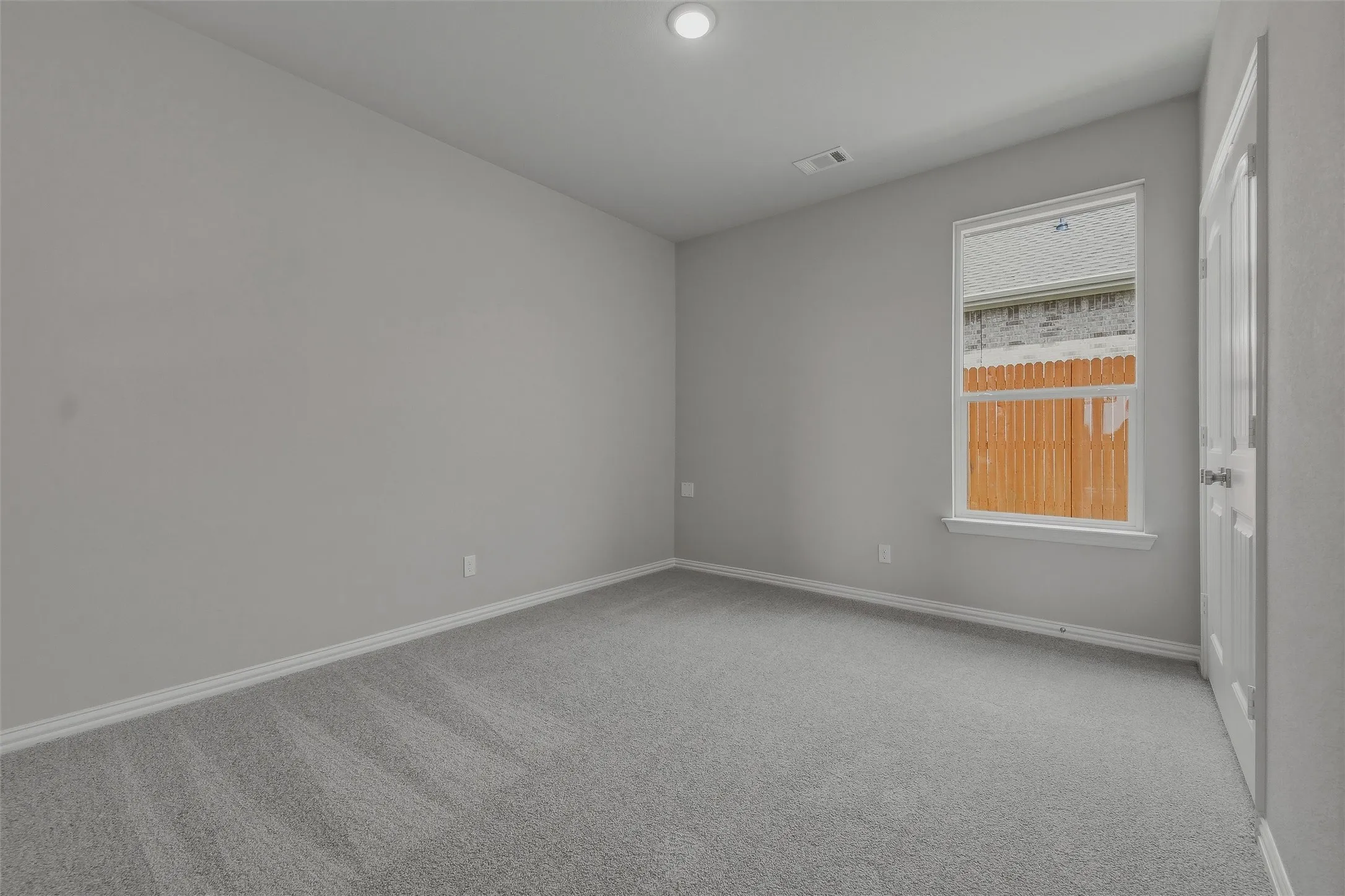 Plush gray carpeting, neutral wall finishes, a single-pane window, and a white interior door