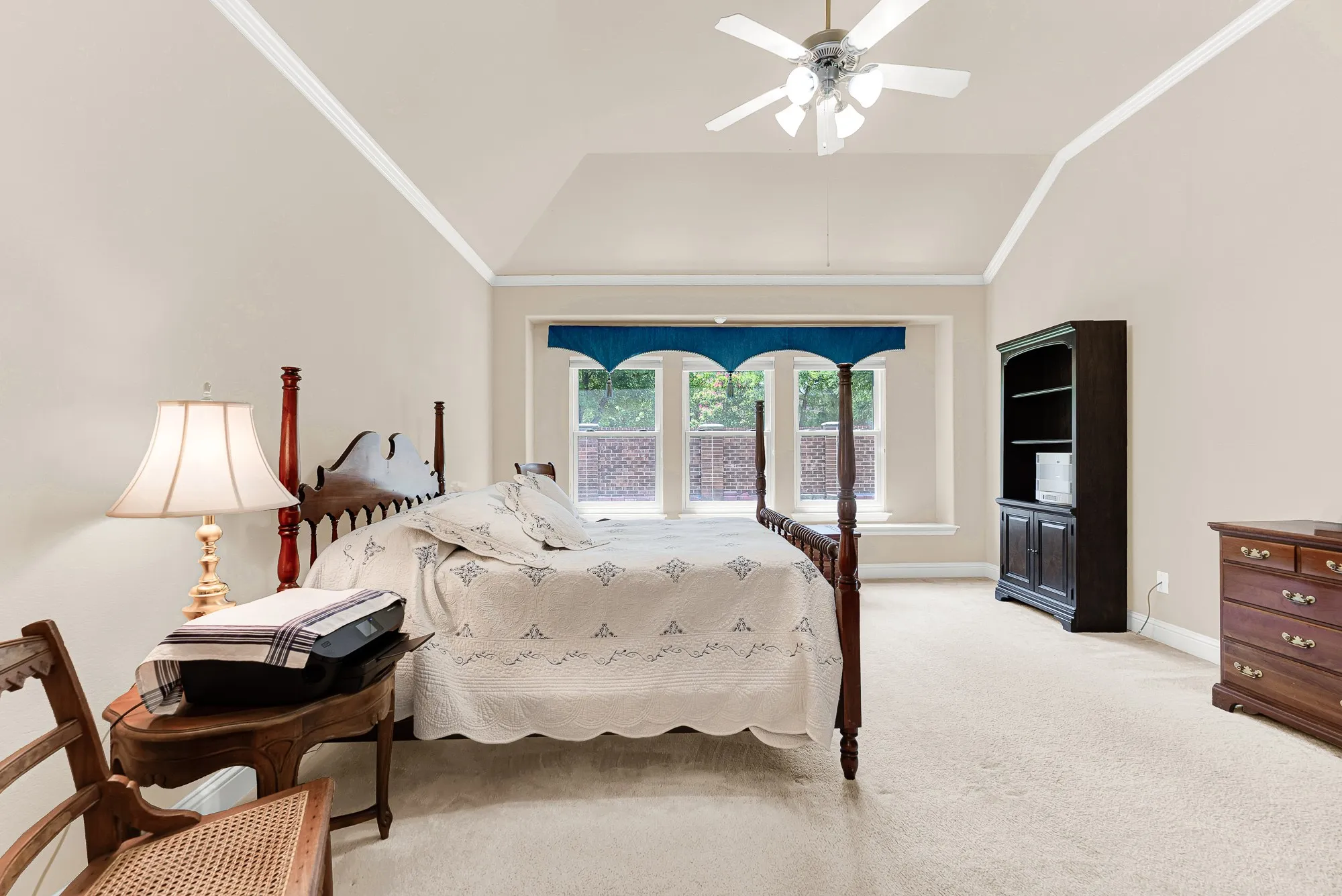Expansive dimensions, elegant crown molding, and a wall of windows make this primary suite feel bright, open, and exceptionally comfortable.