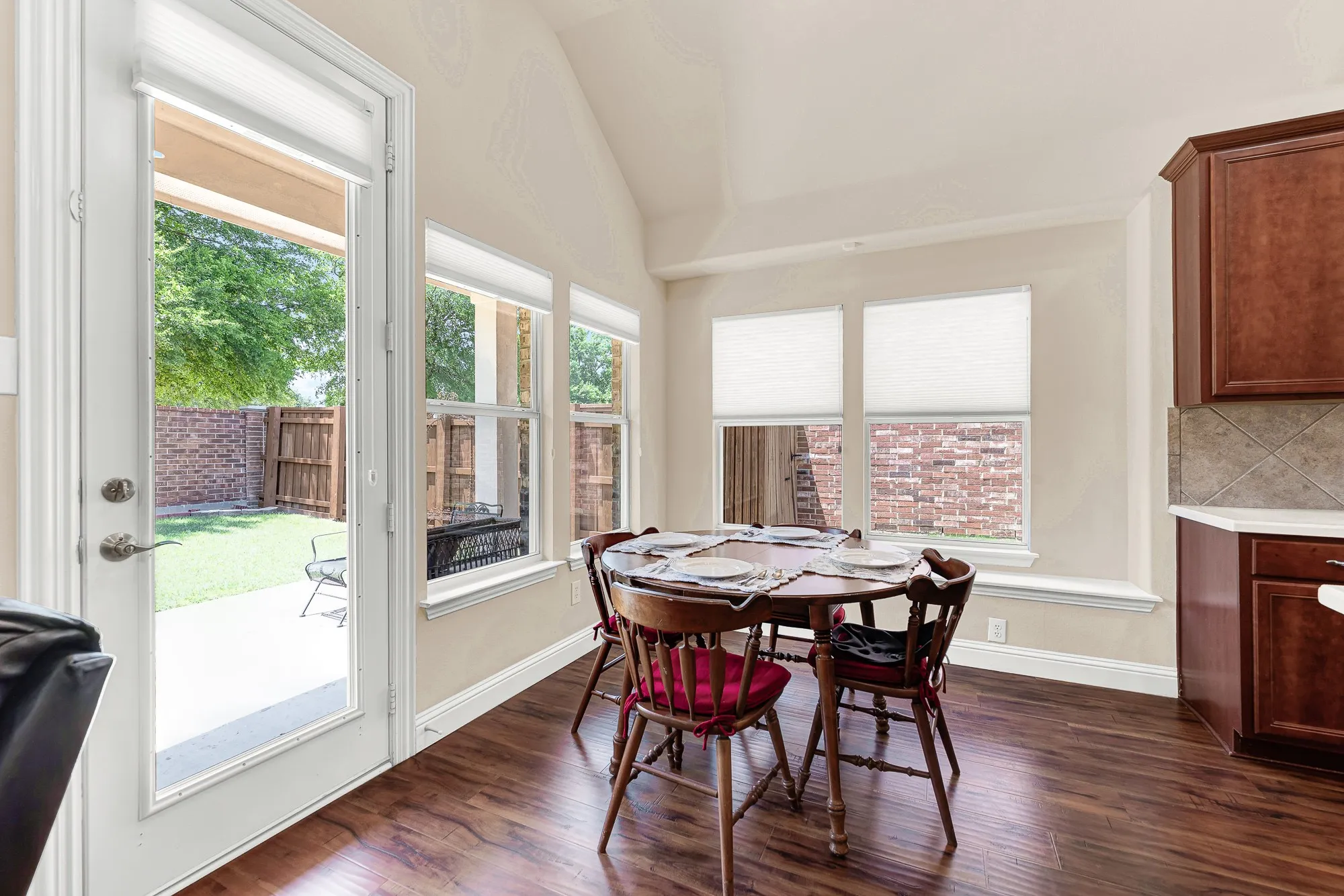 The spacious breakfast area features vaulted ceilings, abundant natural light, and seamless indoor-outdoor living with direct access to the oversized covered patio and backyard.