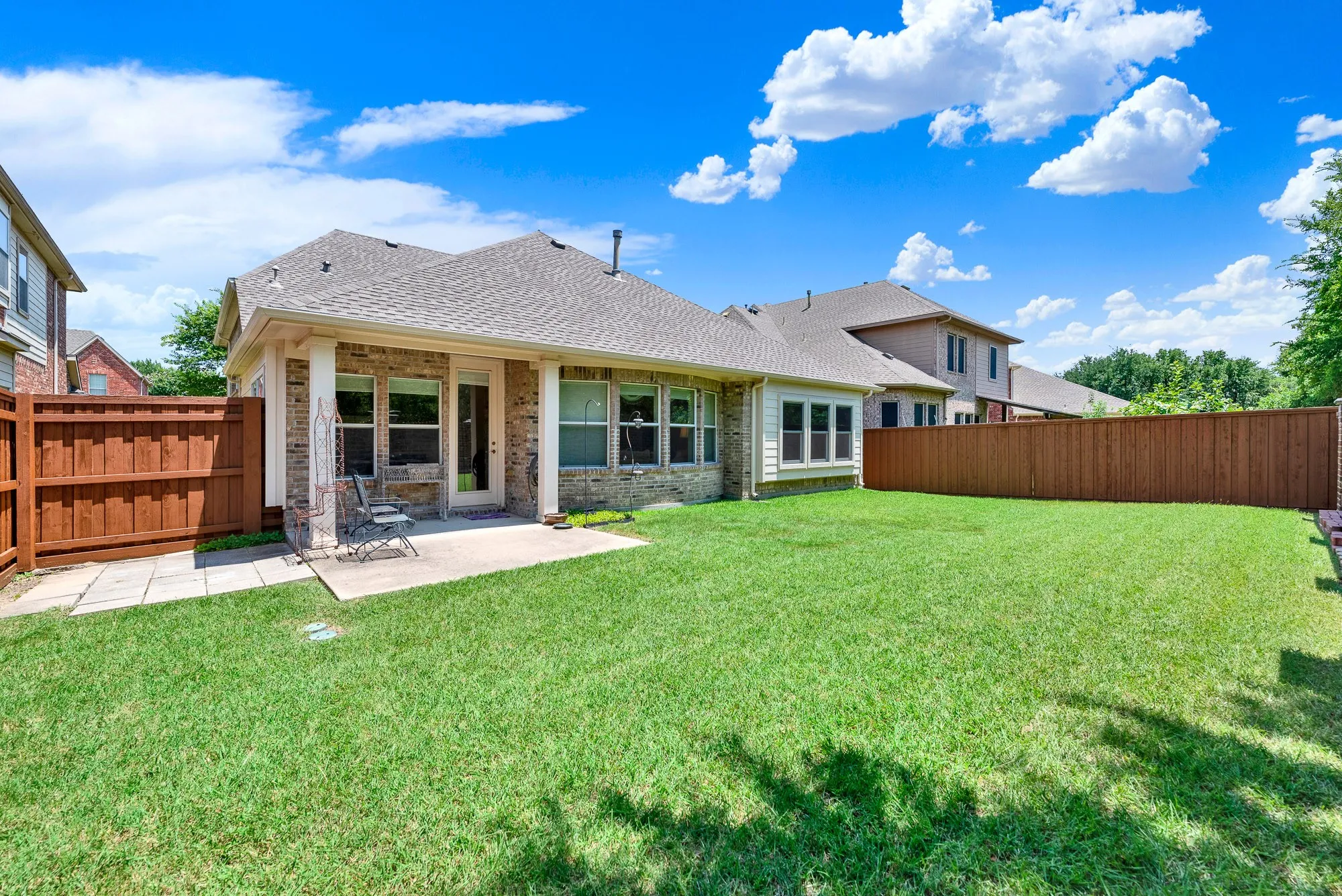 The covered patio provides a comfortable extension of the living space, while the home's rear elevation showcases abundant windows that bring natural light indoors and offer beautiful backyard views.