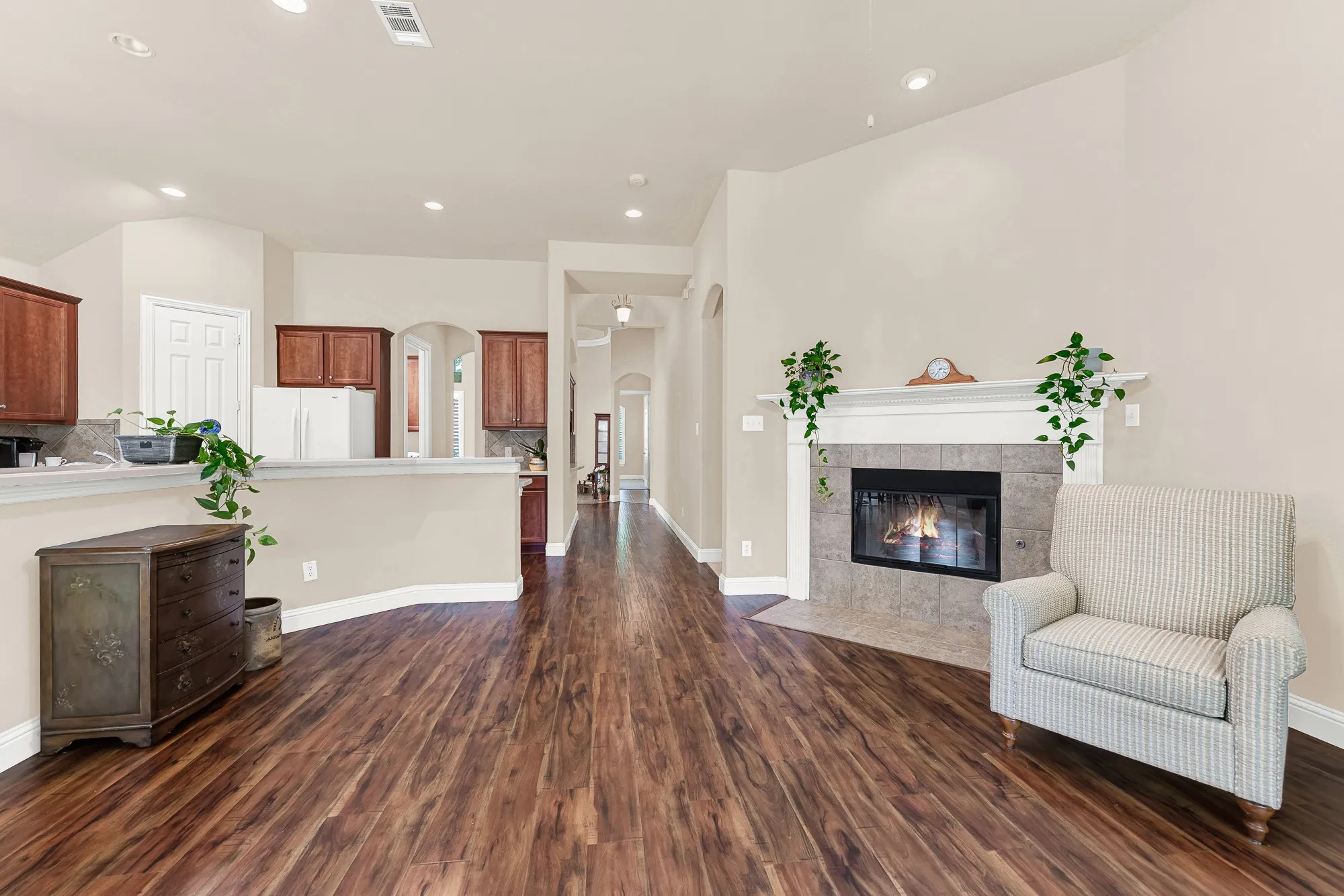 The expansive family room showcases soaring ceilings, rich wood-look flooring, and an open-concept design that seamlessly connects to the kitchen—creating the perfect space for both everyday living and effortless entertaining.