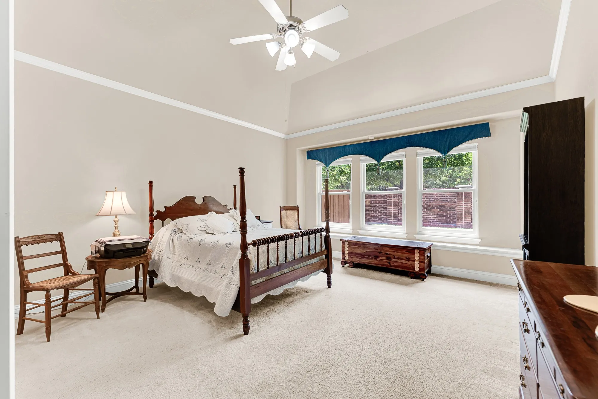 Retreat to the spacious primary suite featuring a vaulted ceiling with crown molding, abundant natural light, and a cozy window seat overlooking the backyard—creating a peaceful place to relax.