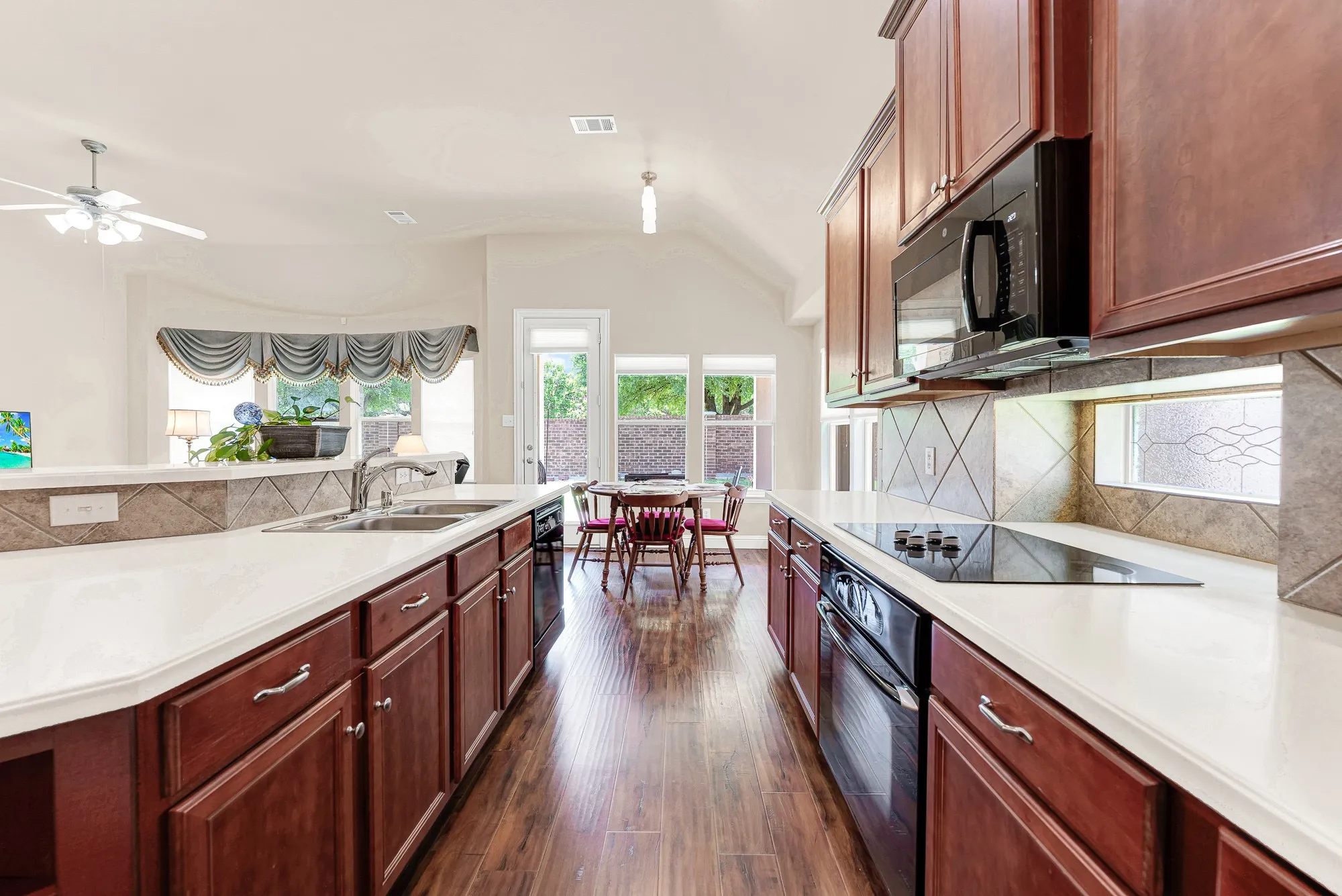 Warm wood cabinetry, extensive counter space, and an intuitive layout create a kitchen that is as beautiful as it is functional, with easy access to the breakfast area and outdoor patio.