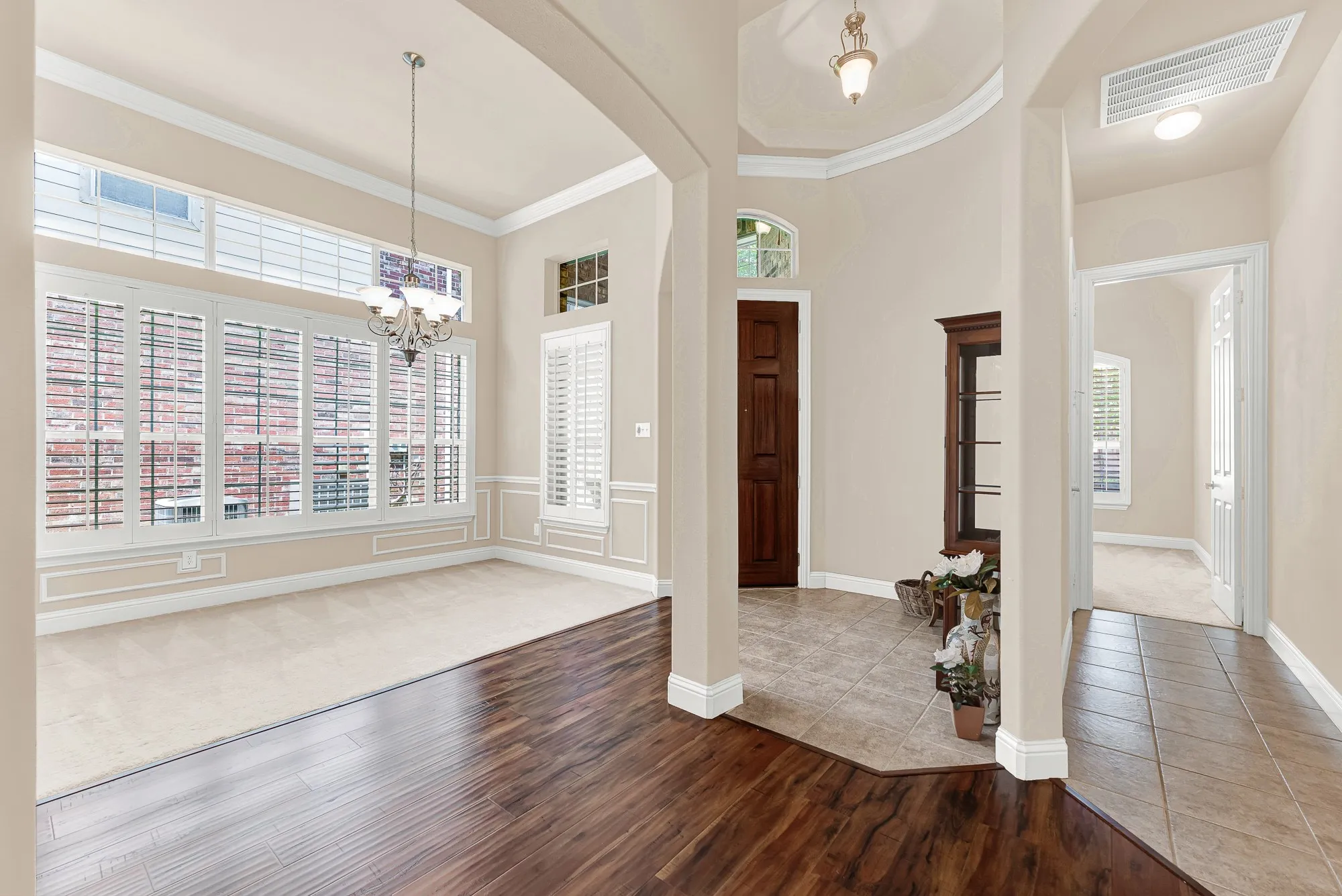 A welcoming view from the entry showcases the elegant formal dining room, highlighted by rich wood flooring, arched openings, custom millwork, and abundant natural light.