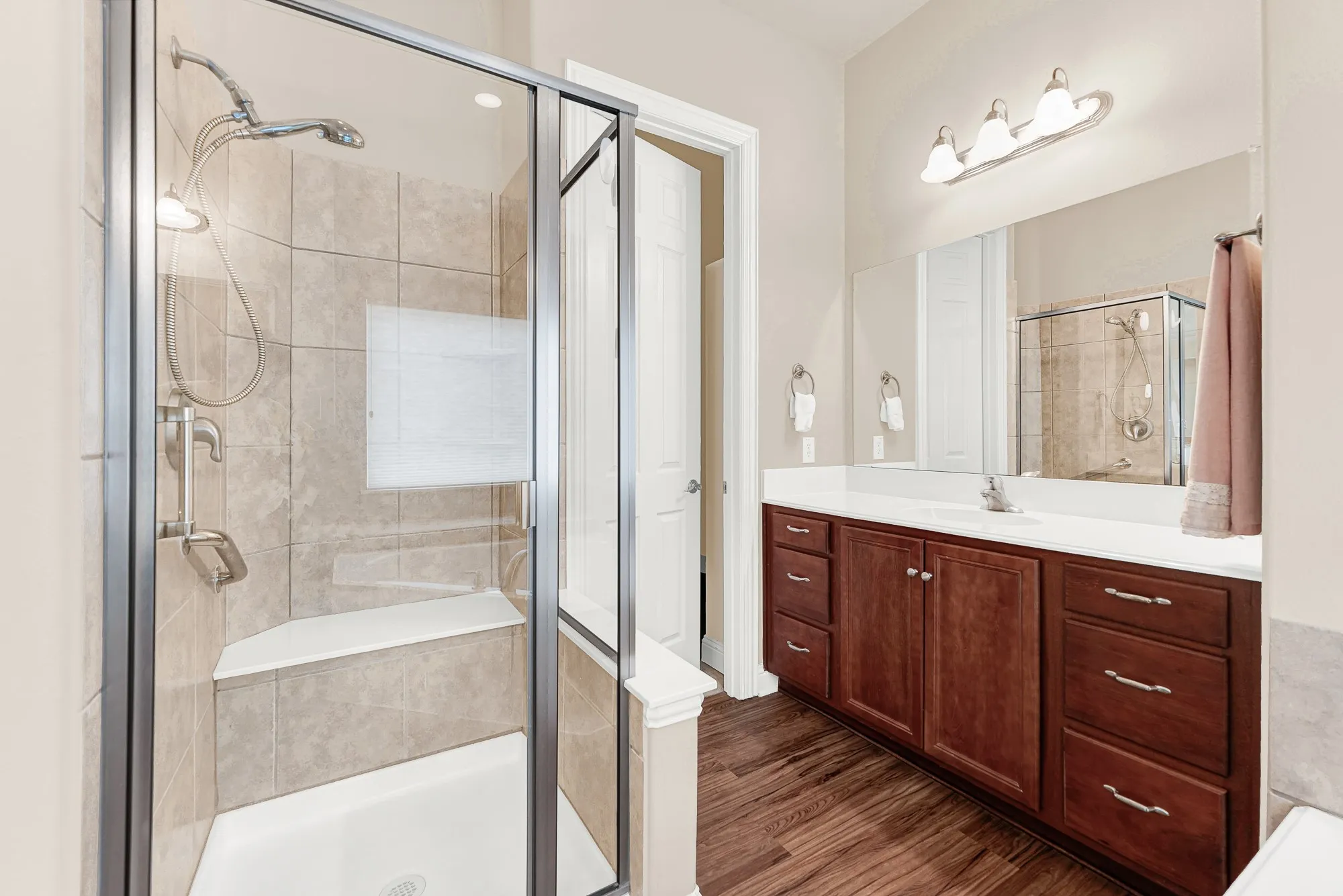 The luxurious primary bath includes a large walk-in shower with built-in bench seating, tile surround, and a separate vanity for added convenience and functionality.