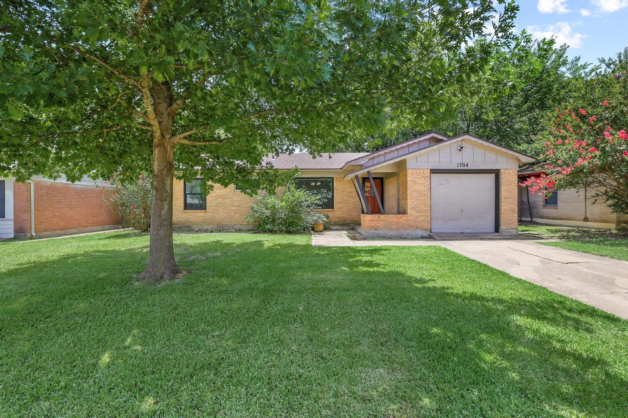 Brick exterior featuring a single-car garage and a concrete driveway