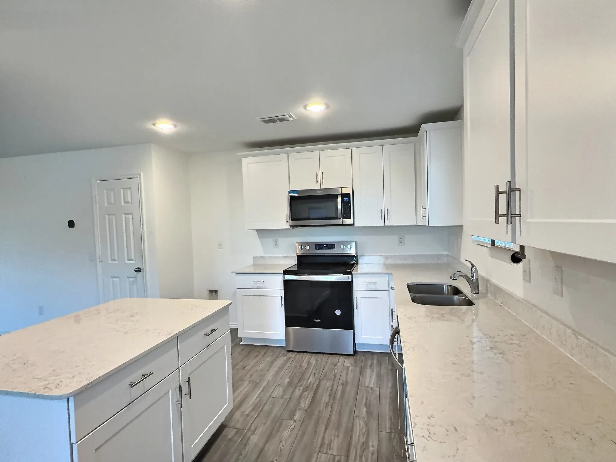 Spacious kitchen with large island, plentiful counter space, and walk in pantry, open to living room and dining area