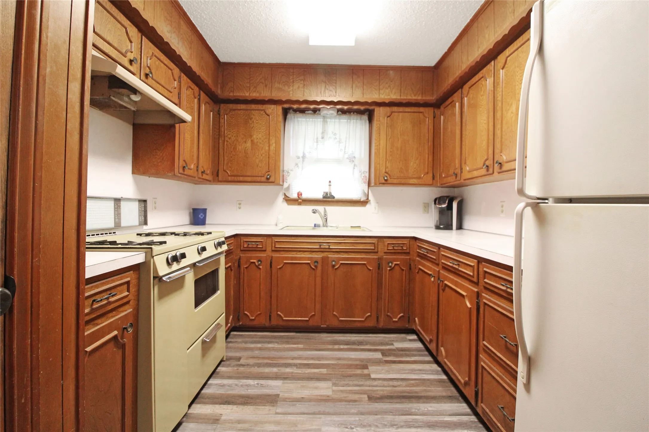 Kitchen featuring extensive wood cabinetry, white countertops, a built-in gas range, a white refrigerator, and wood-finish flooring
