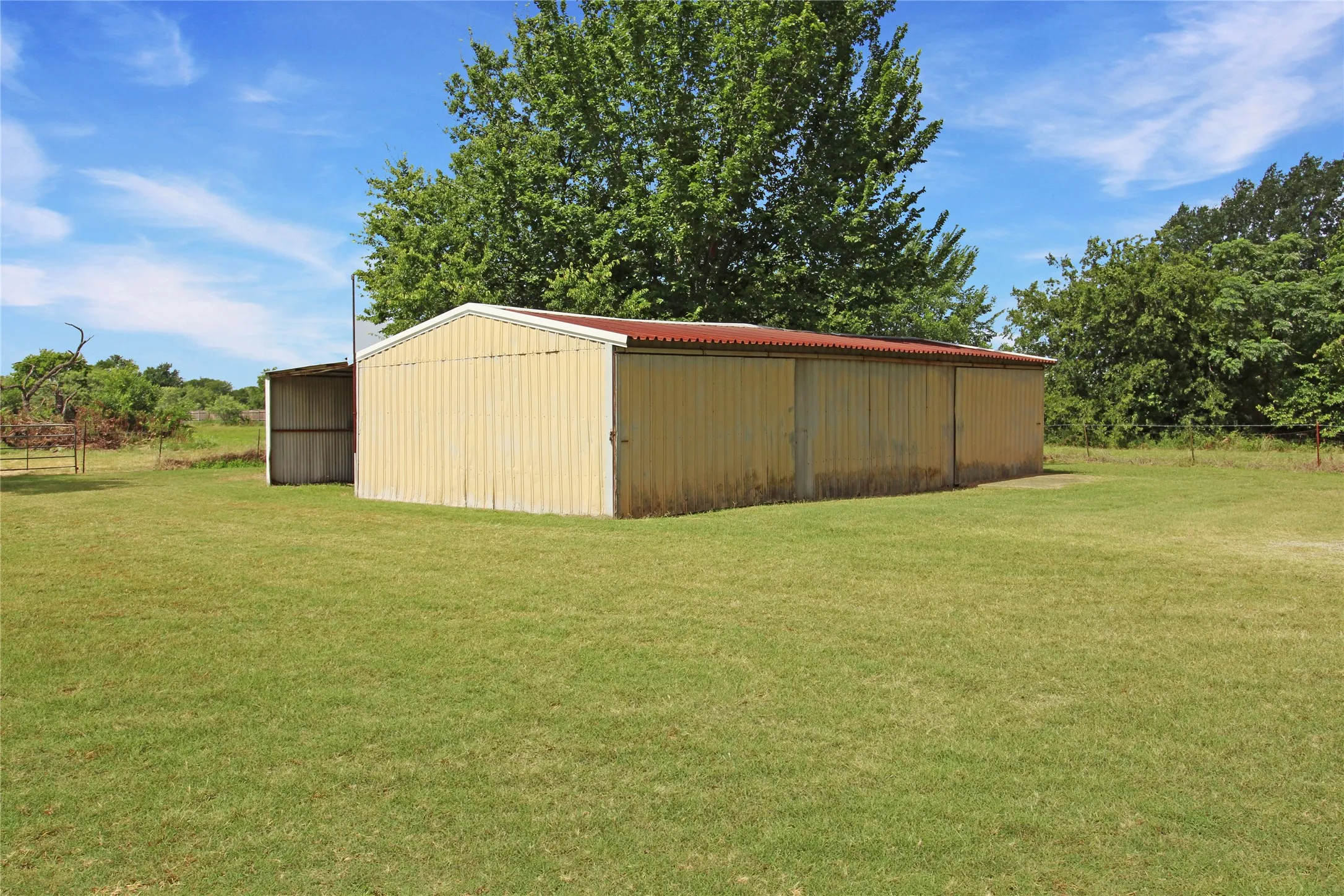 Corrugated metal building with a red roof, featuring an attached lean-to structure