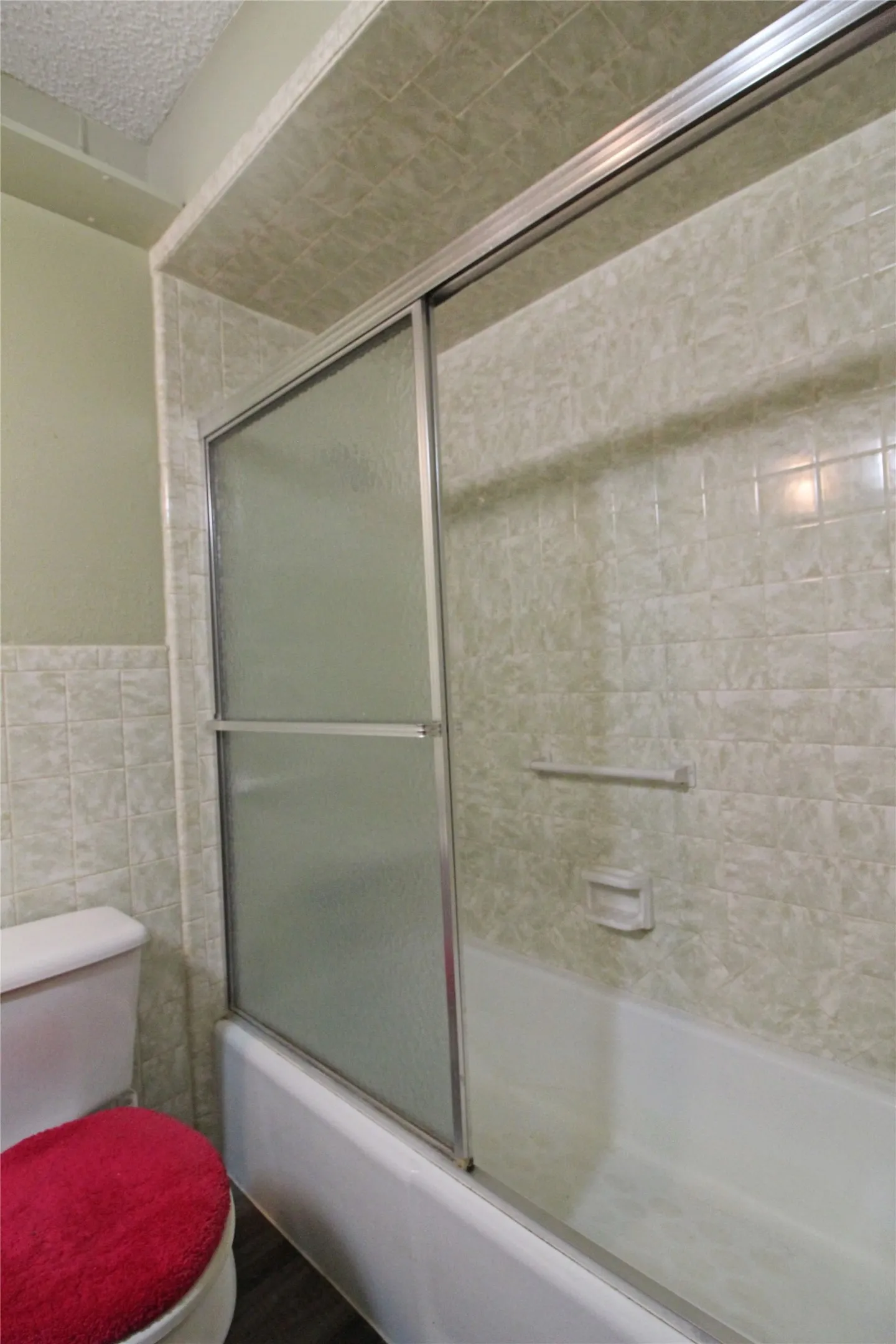 Bathtub with sliding glass shower doors and tiled surround