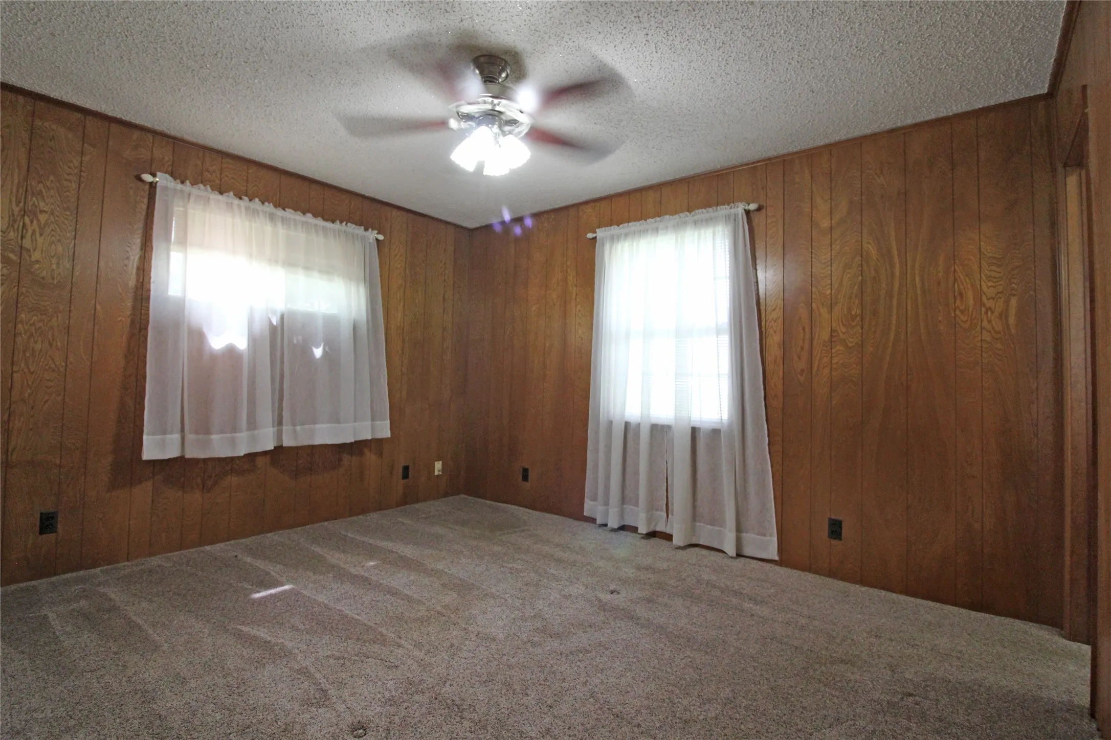Room featuring wood paneling, a textured ceiling, and neutral carpet flooring