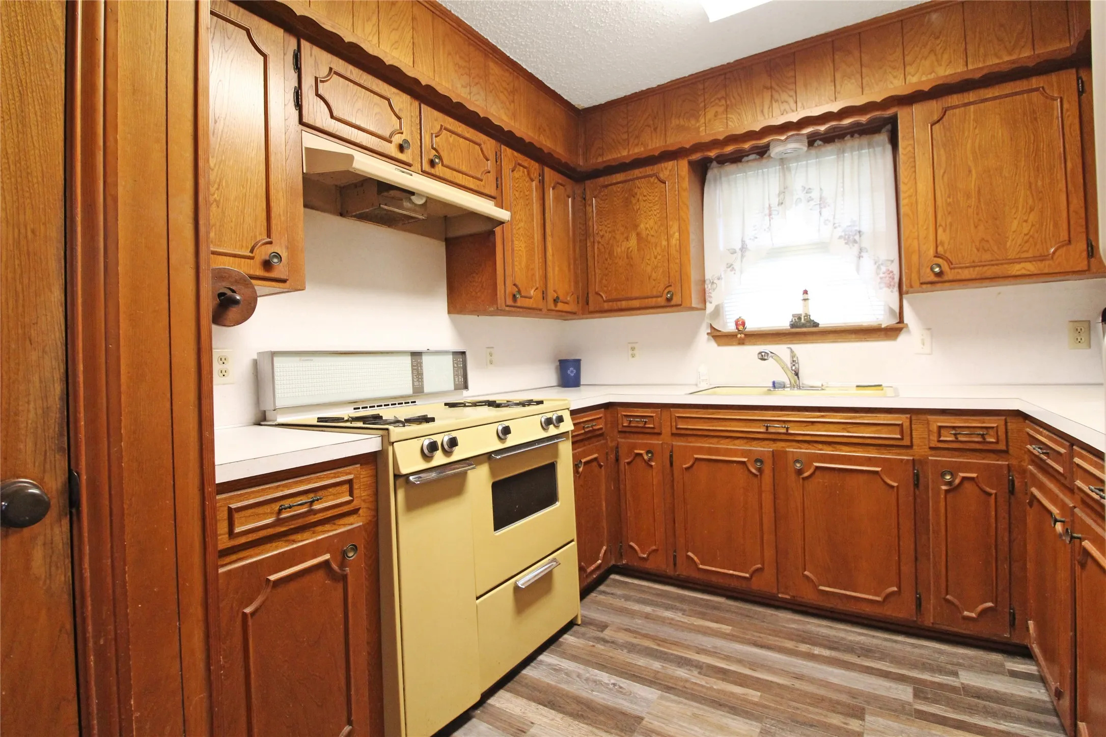 Kitchen featuring wood cabinetry, white countertops, built-in sink, and wood-finish flooring