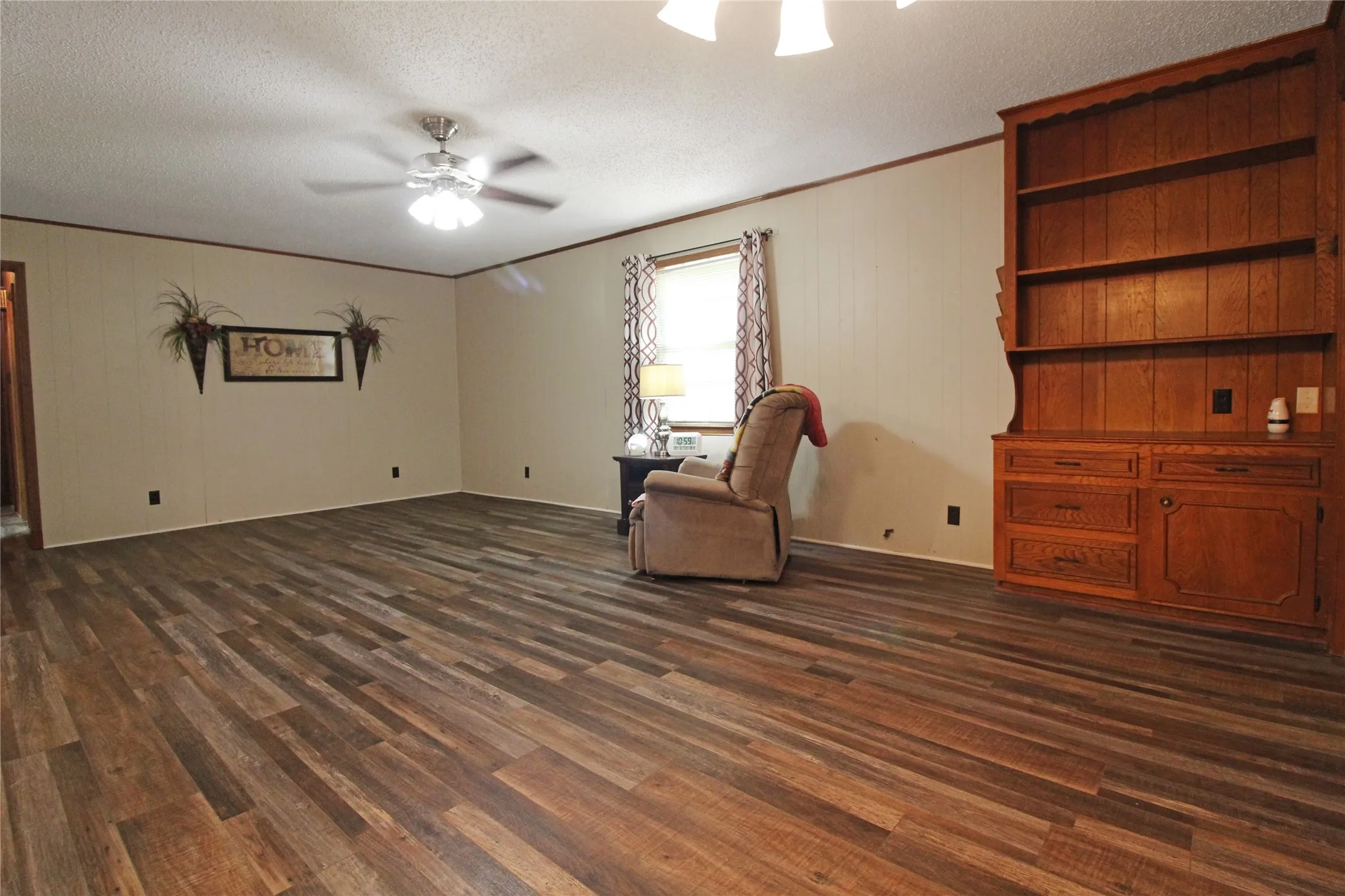 Spacious room featuring multi-tone wood-finish flooring and a ceiling fan with integrated lighting