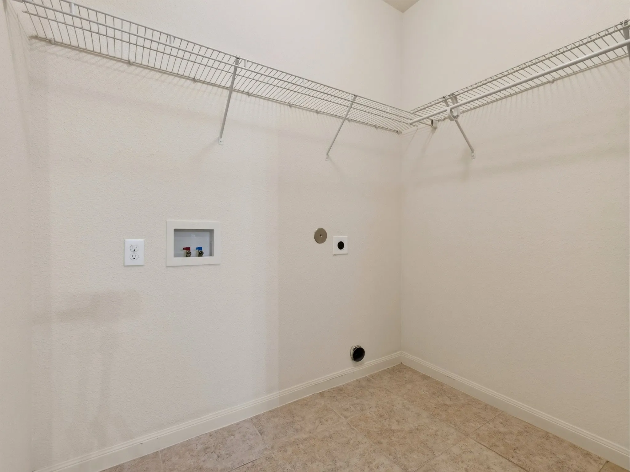Utility area featuring neutral-toned walls, tile flooring, and integrated wire shelving