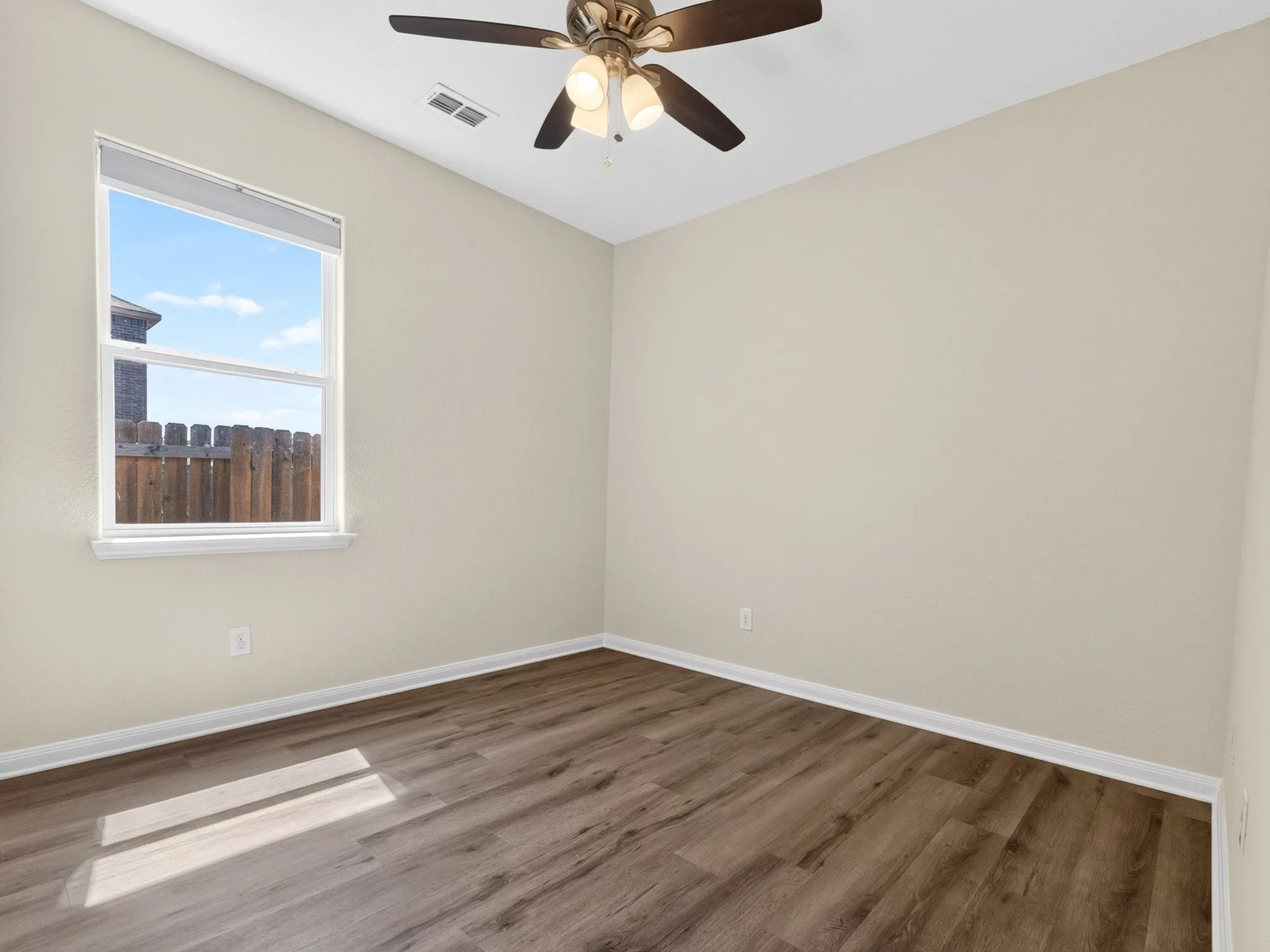 Room with wood-finish flooring, a contemporary ceiling fan with integrated lighting, and a large window