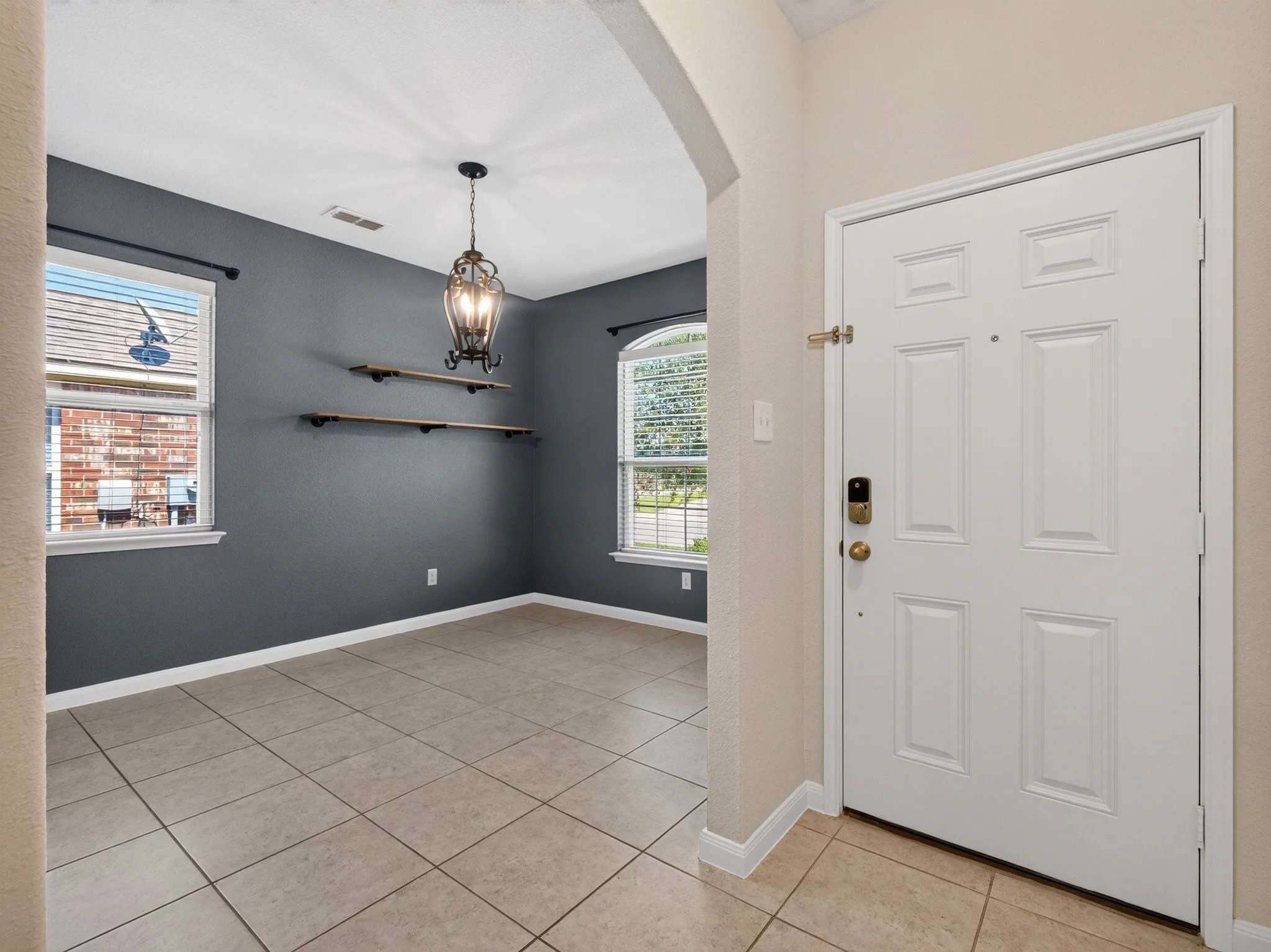 Entryway featuring a panel door with smart lock, arched doorway, and neutral tile flooring