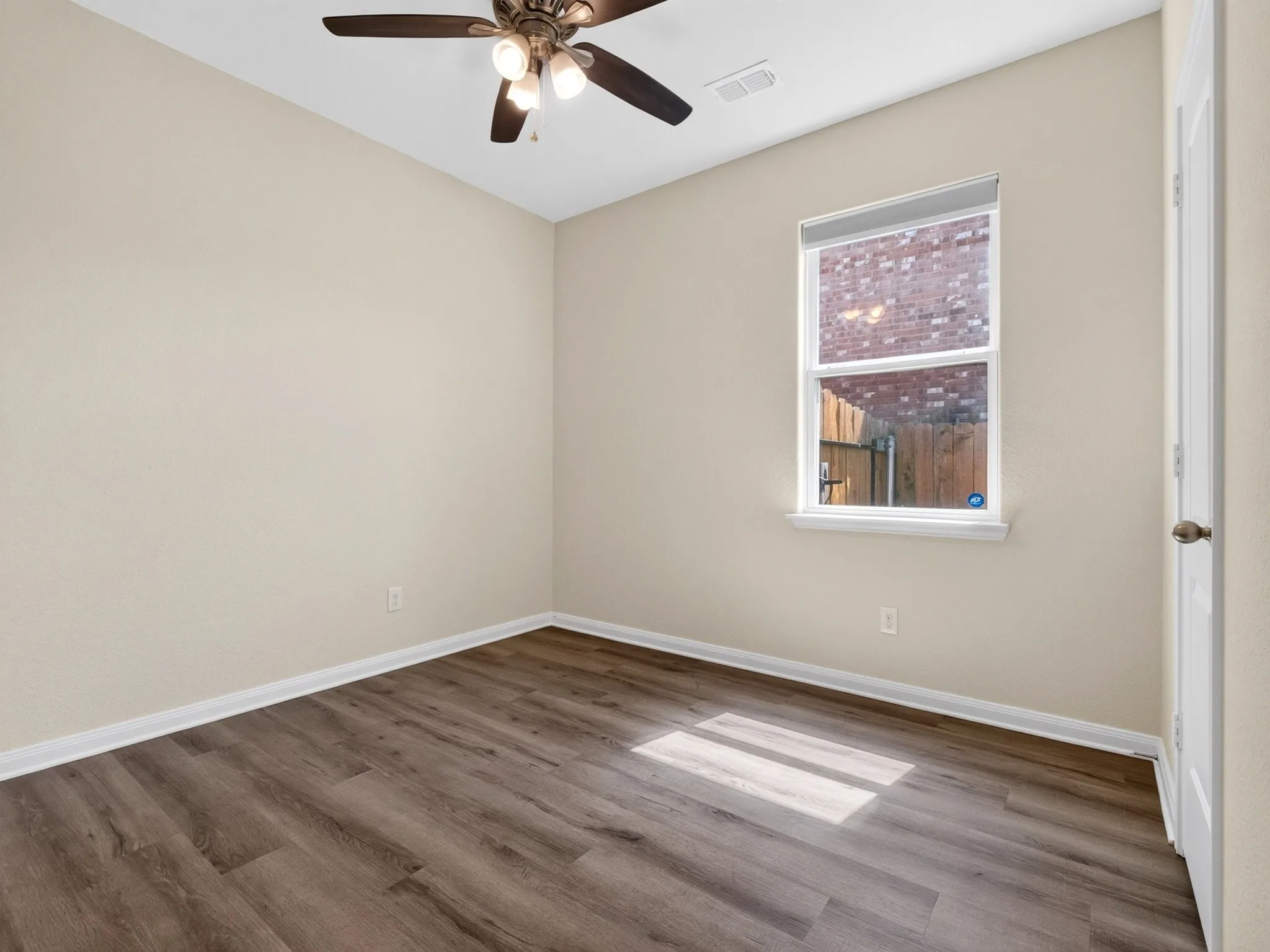 Interior room featuring wood-finish flooring, light neutral-toned walls, and white baseboards