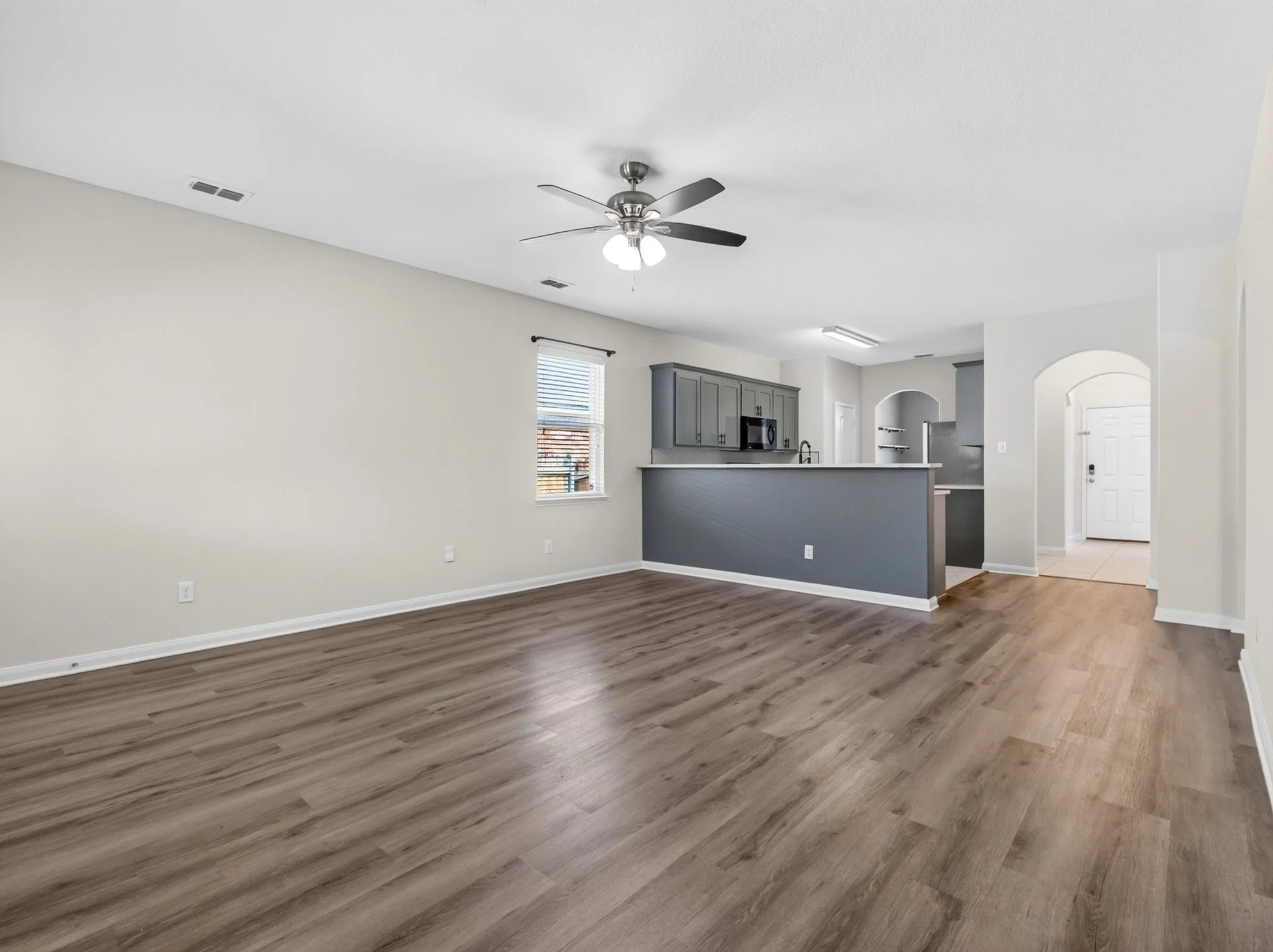 Open-concept living area featuring wood-finish flooring and a ceiling fan