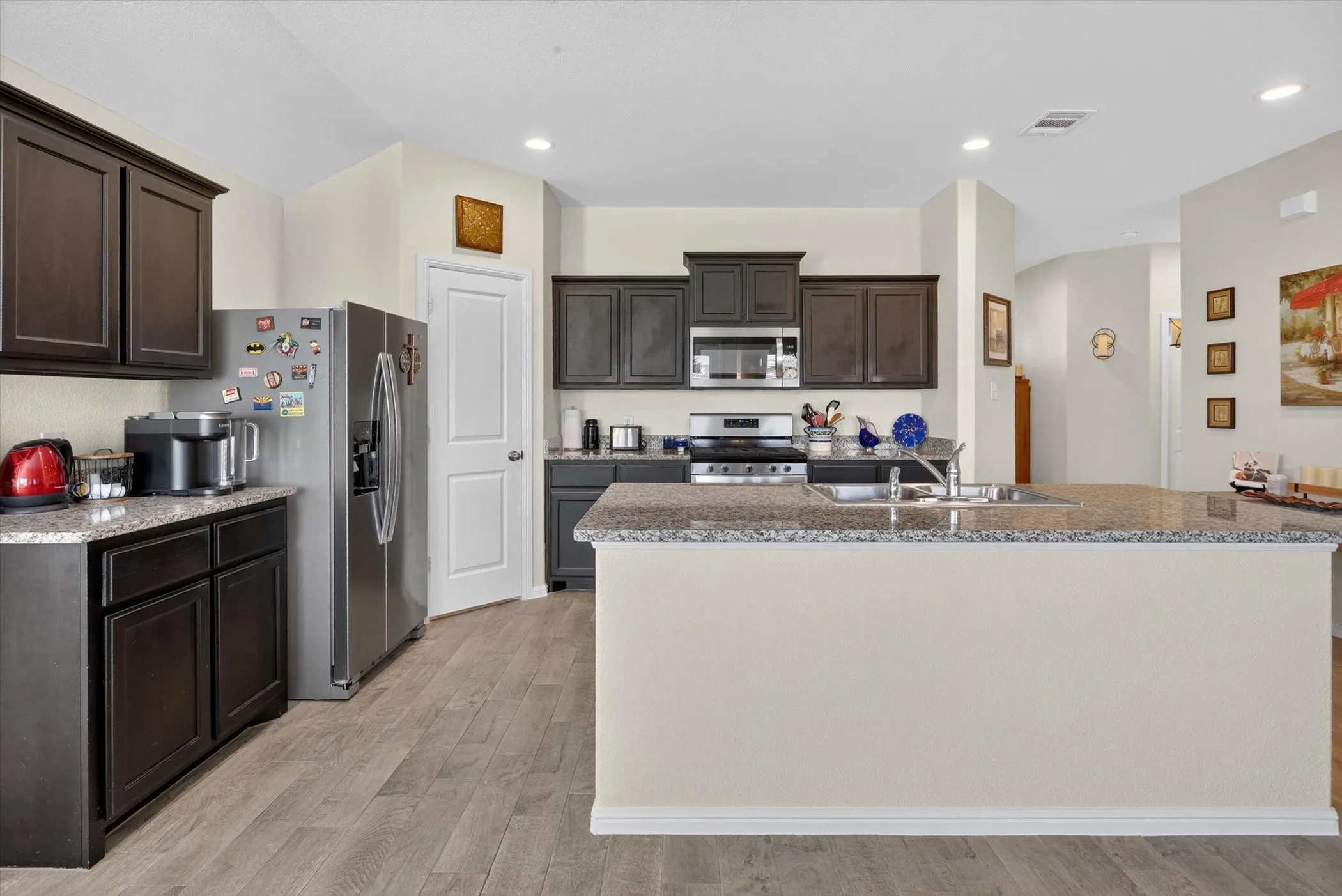 Kitchen featuring dark wood cabinetry, light-toned countertops, and stainless steel appliances