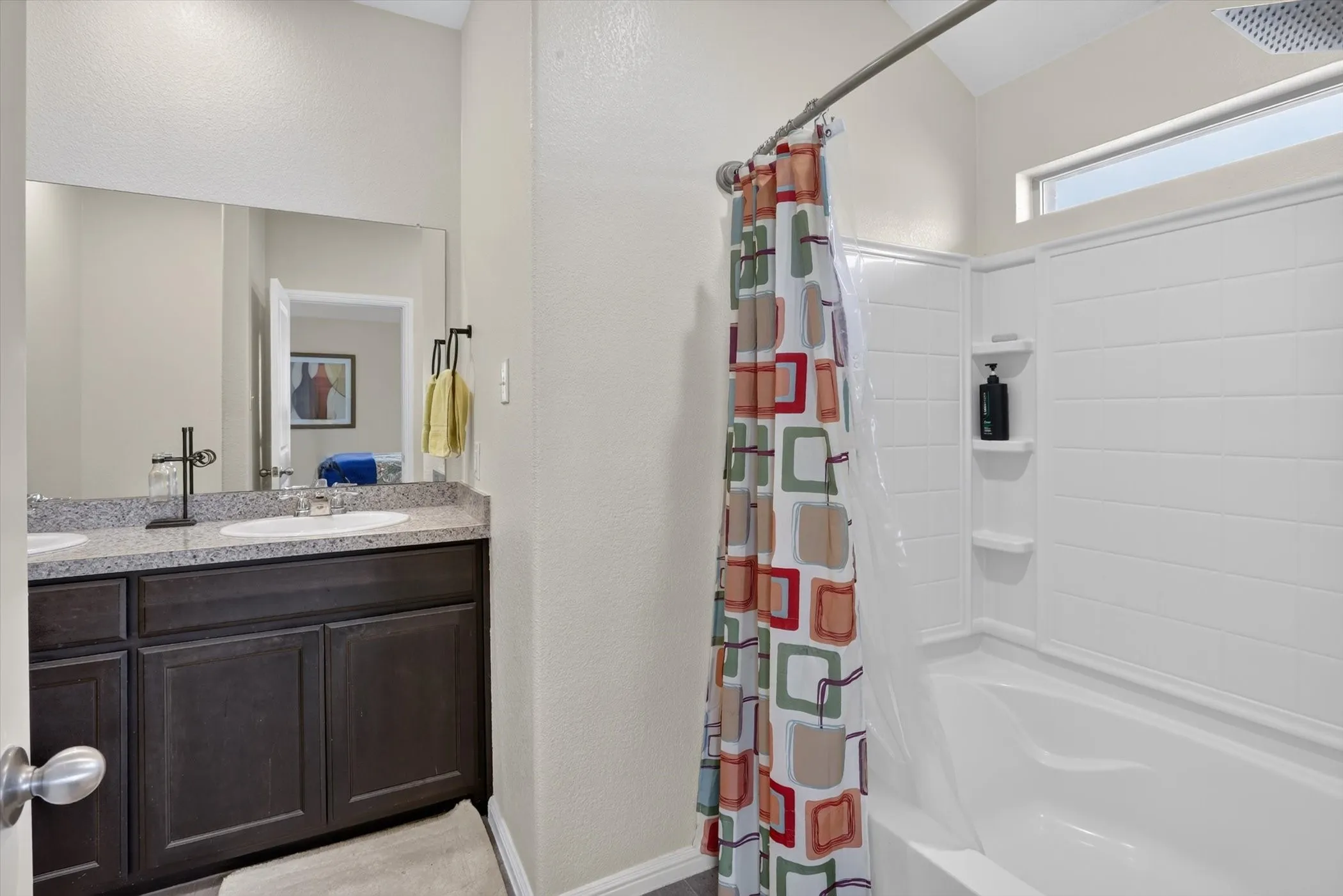 Double vanity with a speckled countertop and dark wood-finish cabinetry