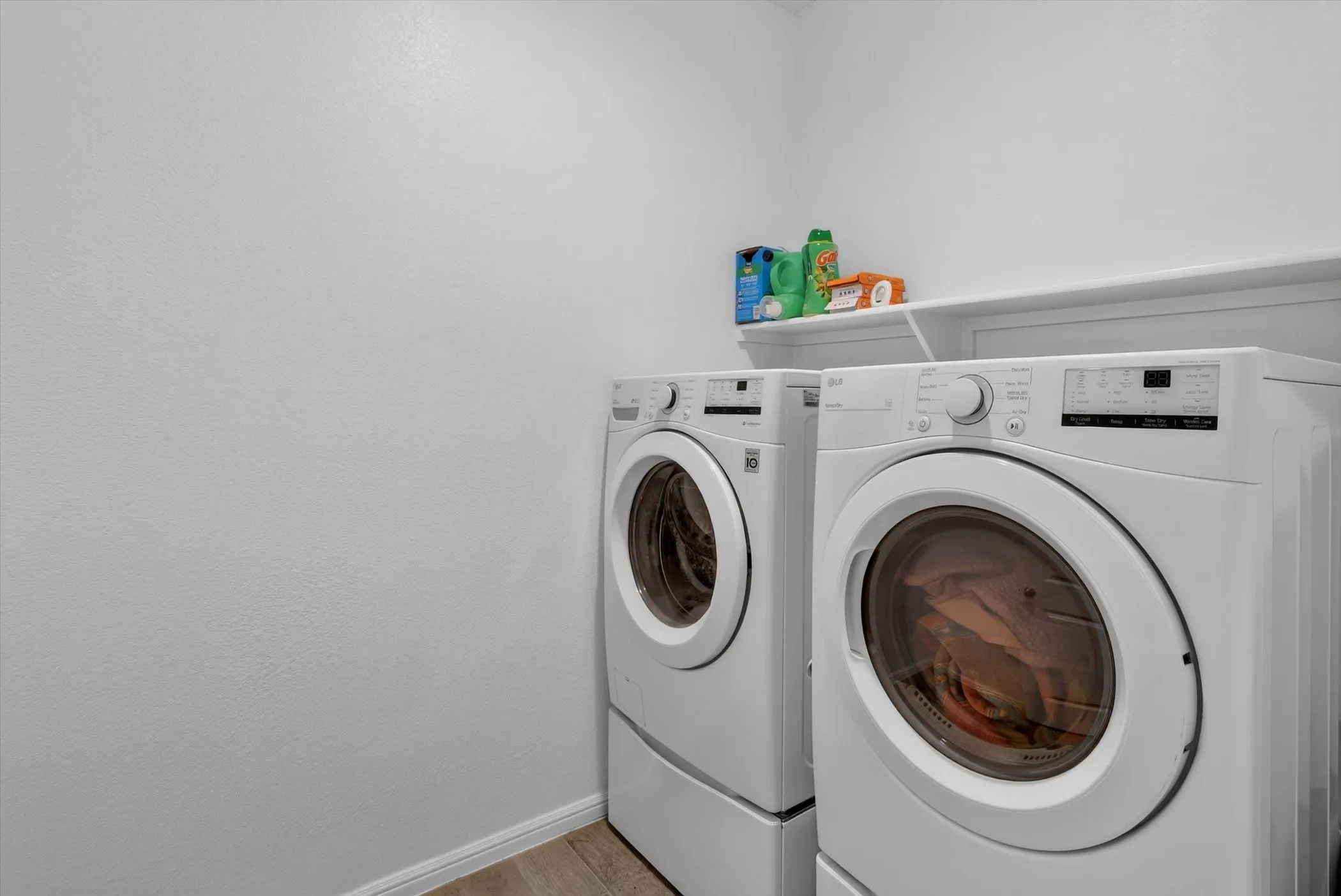 Dedicated laundry area featuring white walls, wood-finish flooring, and built-in shelving