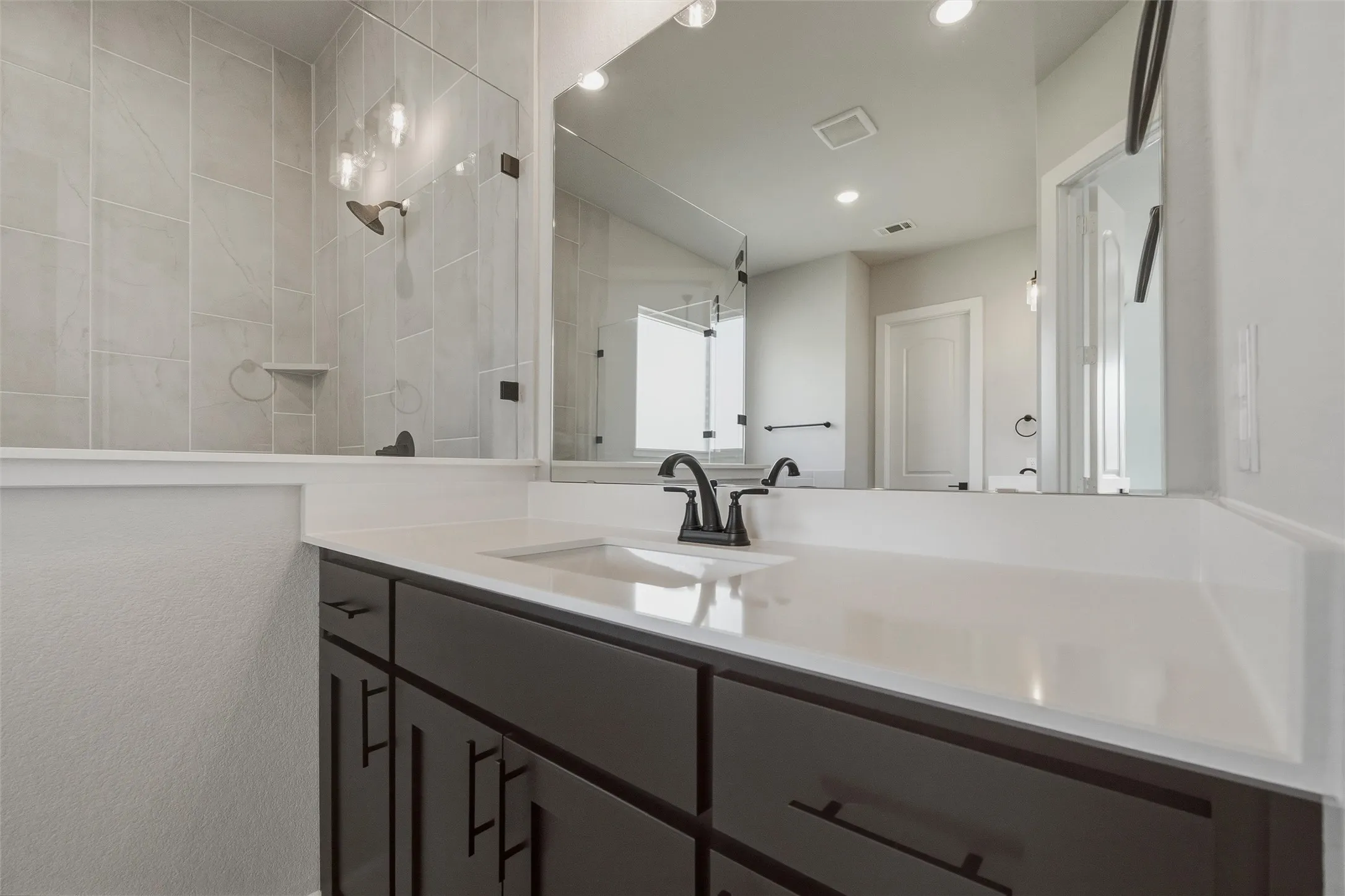 Dark wood vanity with a white solid surface countertop, undermount sink, and matte black faucet