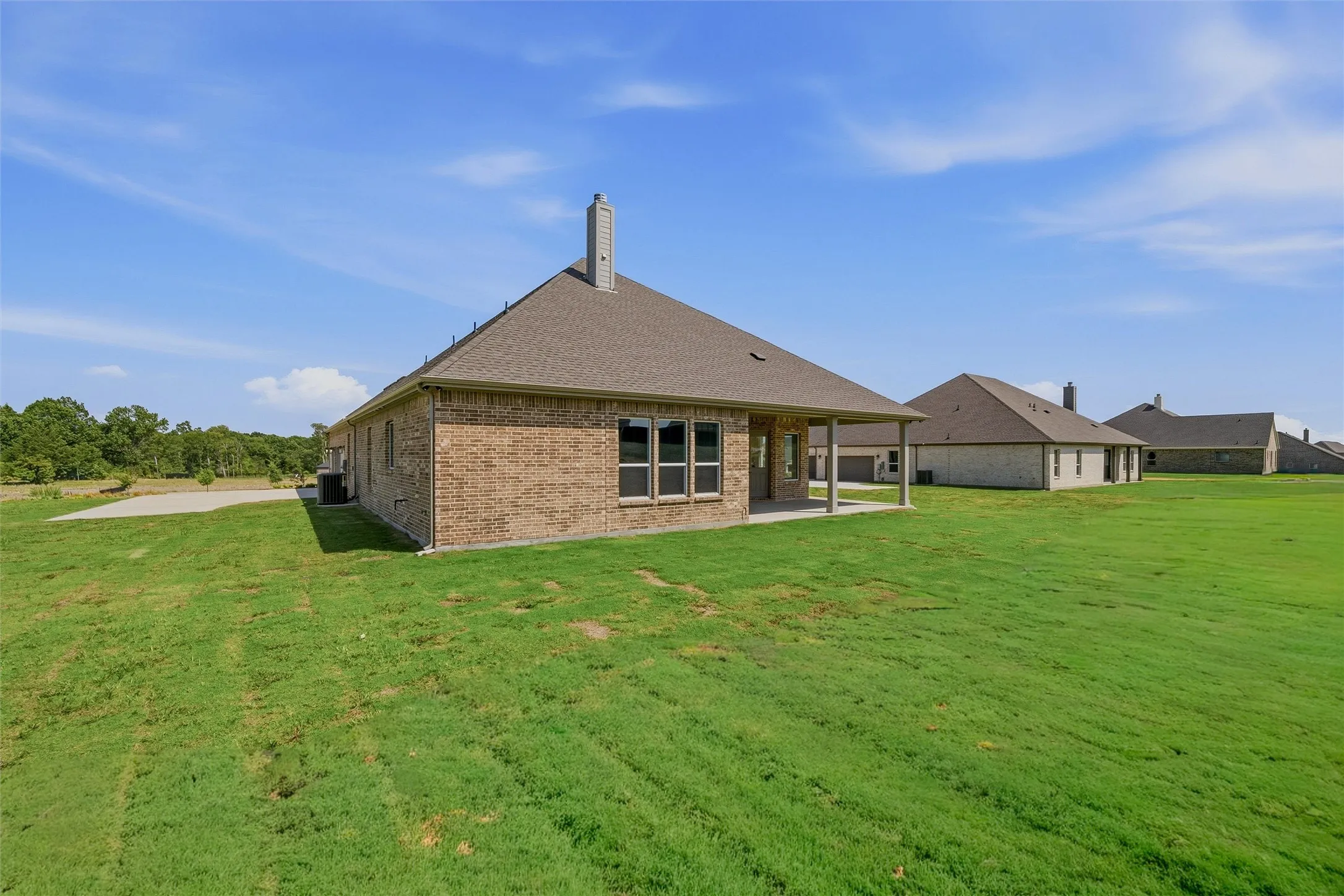 Brick exterior with a covered patio and a large concrete slab