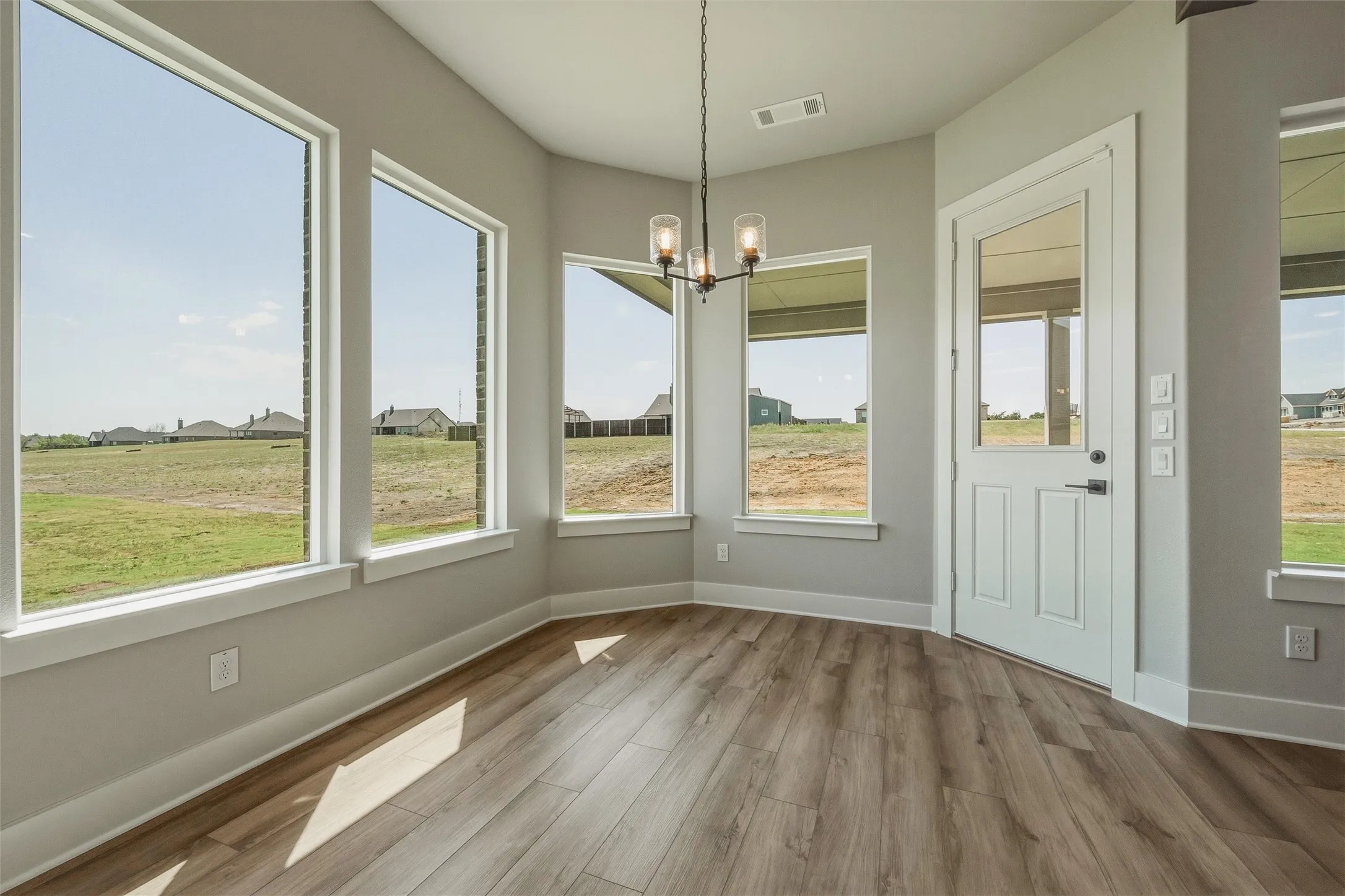 Multiple large windows, wood-finish flooring, and a glass-paneled exterior door