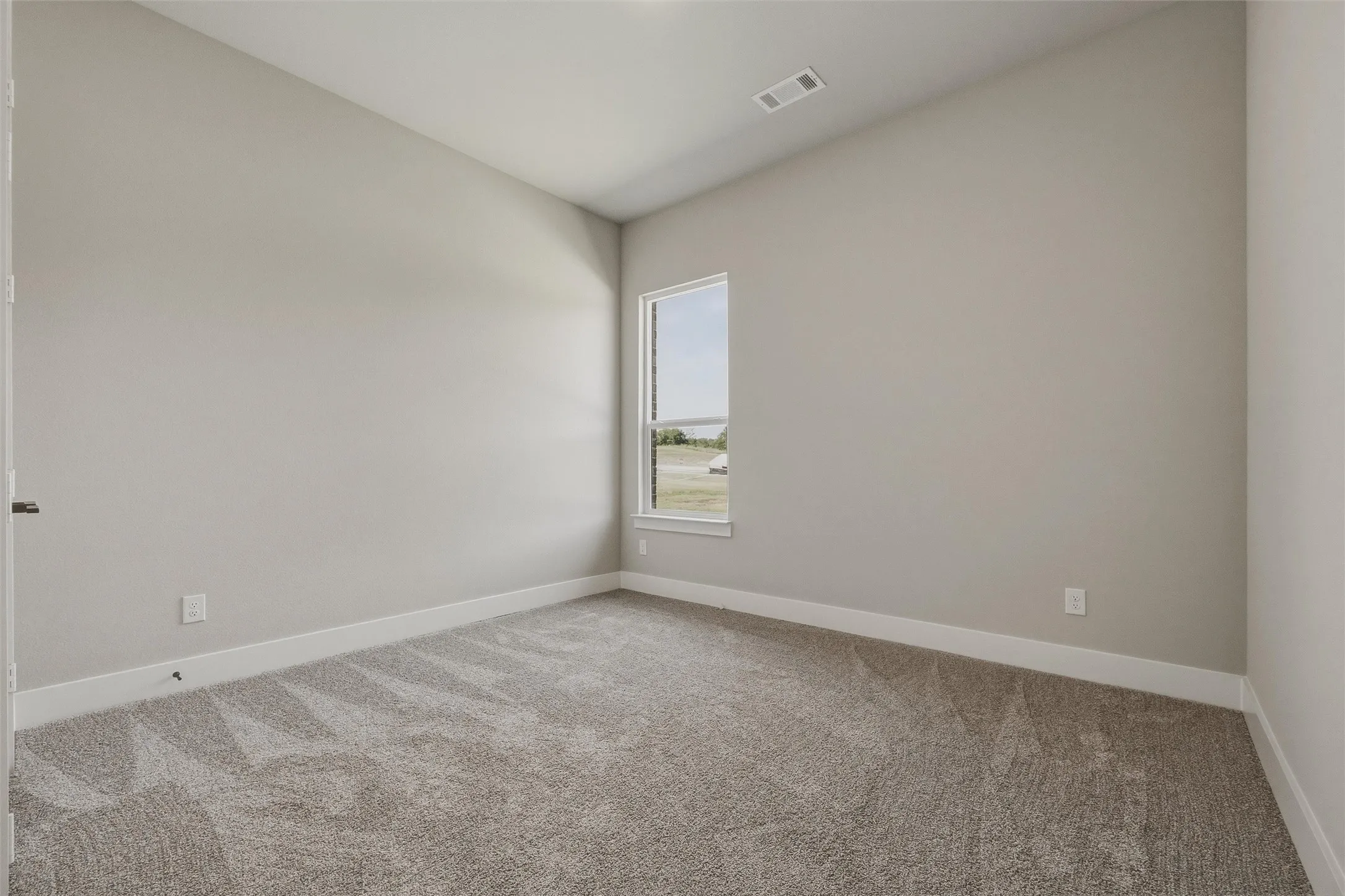Neutral paint tones, carpeted flooring, a single window, and a white trim