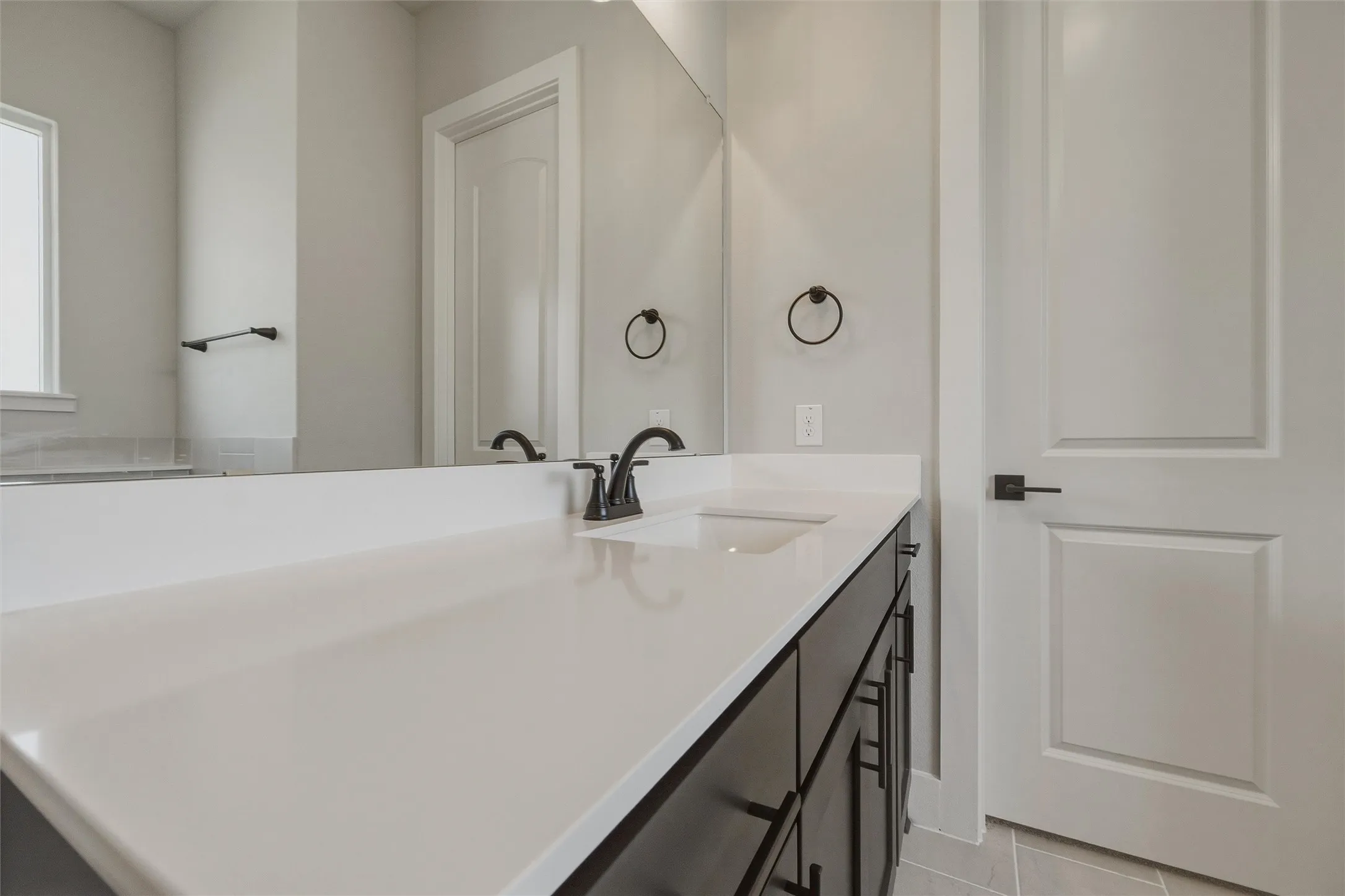 Vanity with a white countertop, undermount sink, and dark wood-finish cabinetry