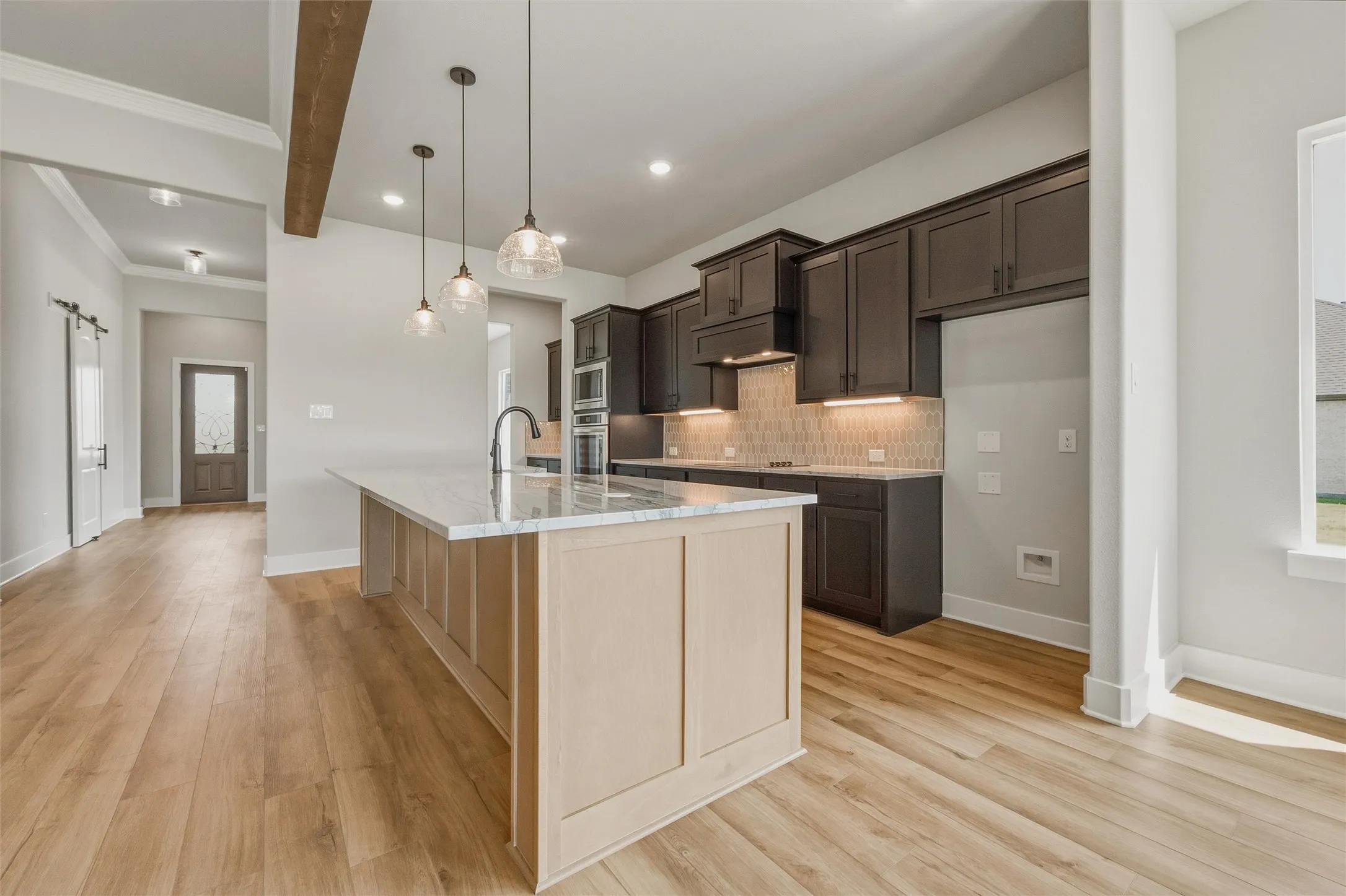 Kitchen with a large island, dark wood-finish cabinetry, and under-cabinet lighting