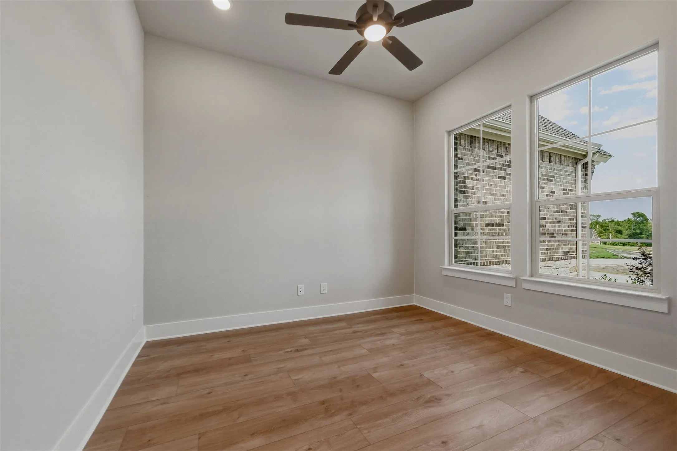 Vaulted ceiling, wood-finish flooring, ceiling fan with integrated lighting, recessed lighting, and large windows