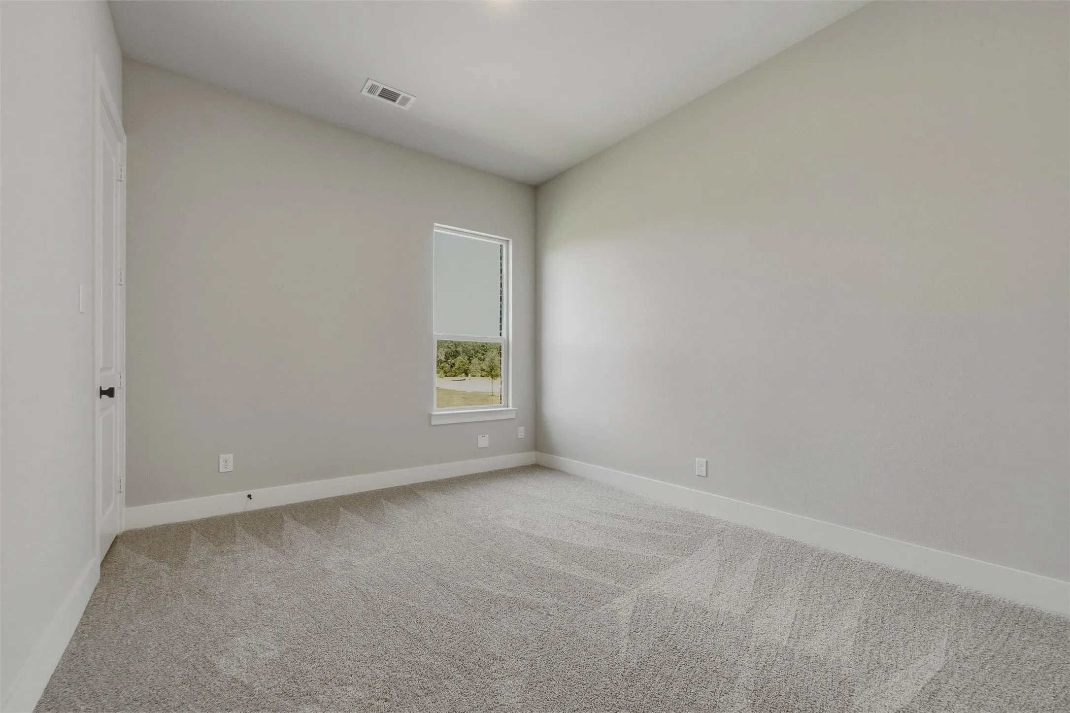 Carpeted room with a single window, white trim, and light gray walls