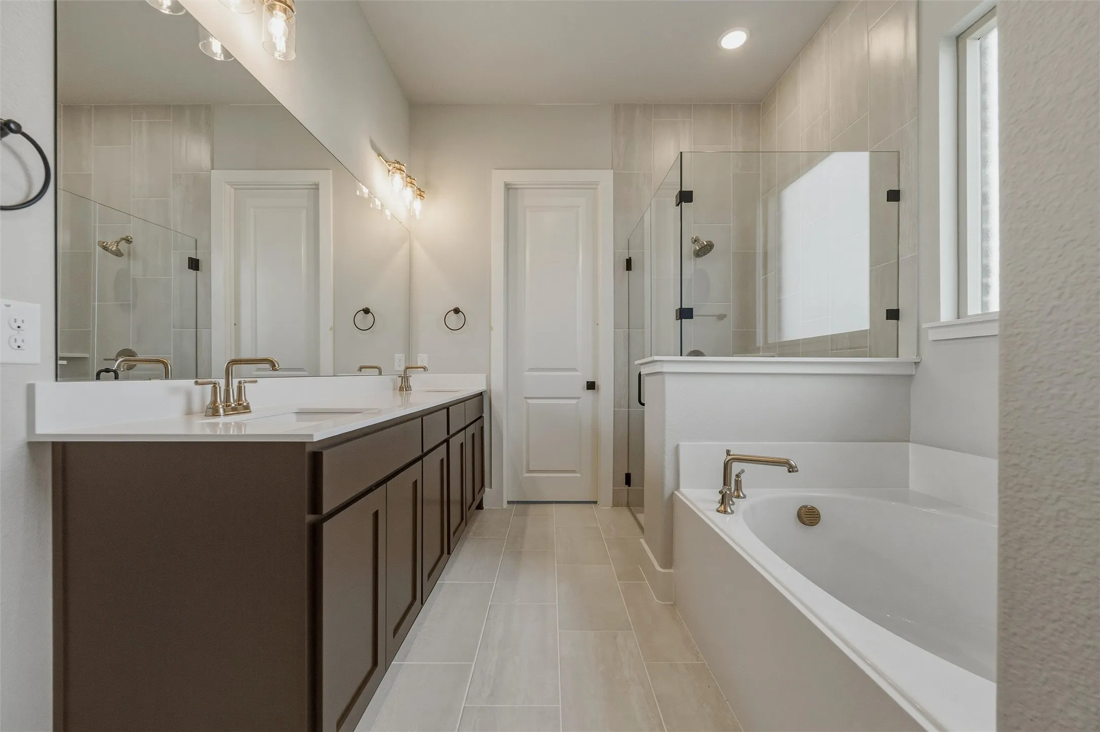 Double vanity with dark wood-finish cabinetry, white countertops, and gold-finish fixtures