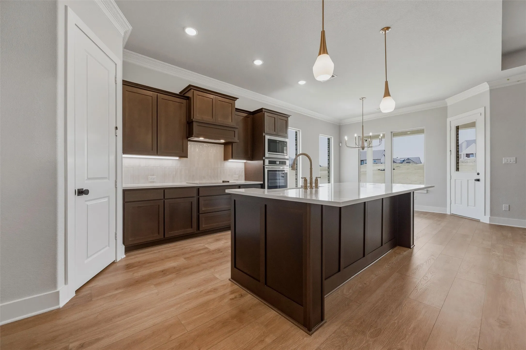 Kitchen featuring wood-finish flooring, dark wood cabinetry, white countertops, and stainless steel appliances