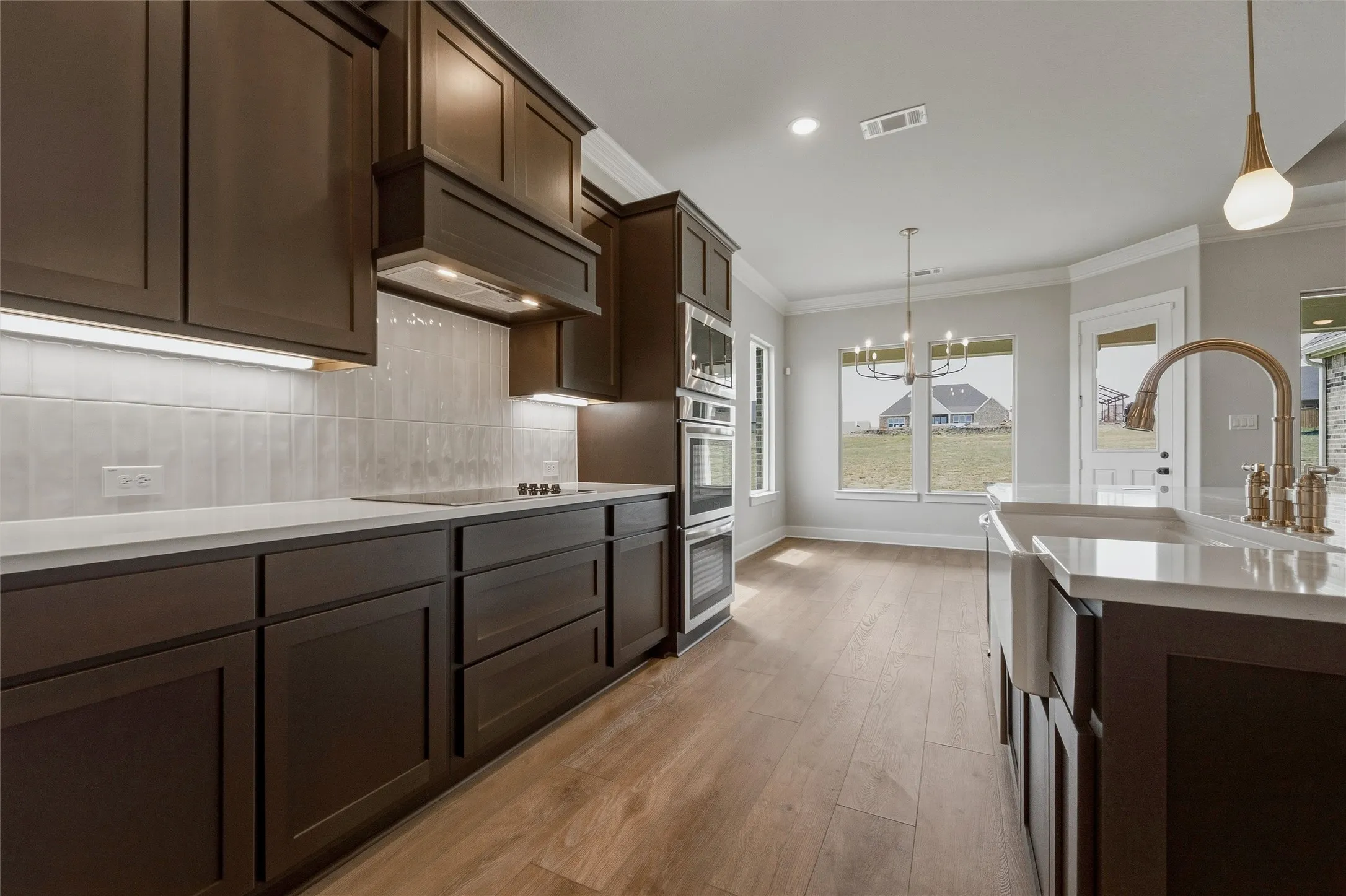 Kitchen featuring dark wood-finish cabinetry, light countertops, subway tile backsplash, and wood-finish flooring
