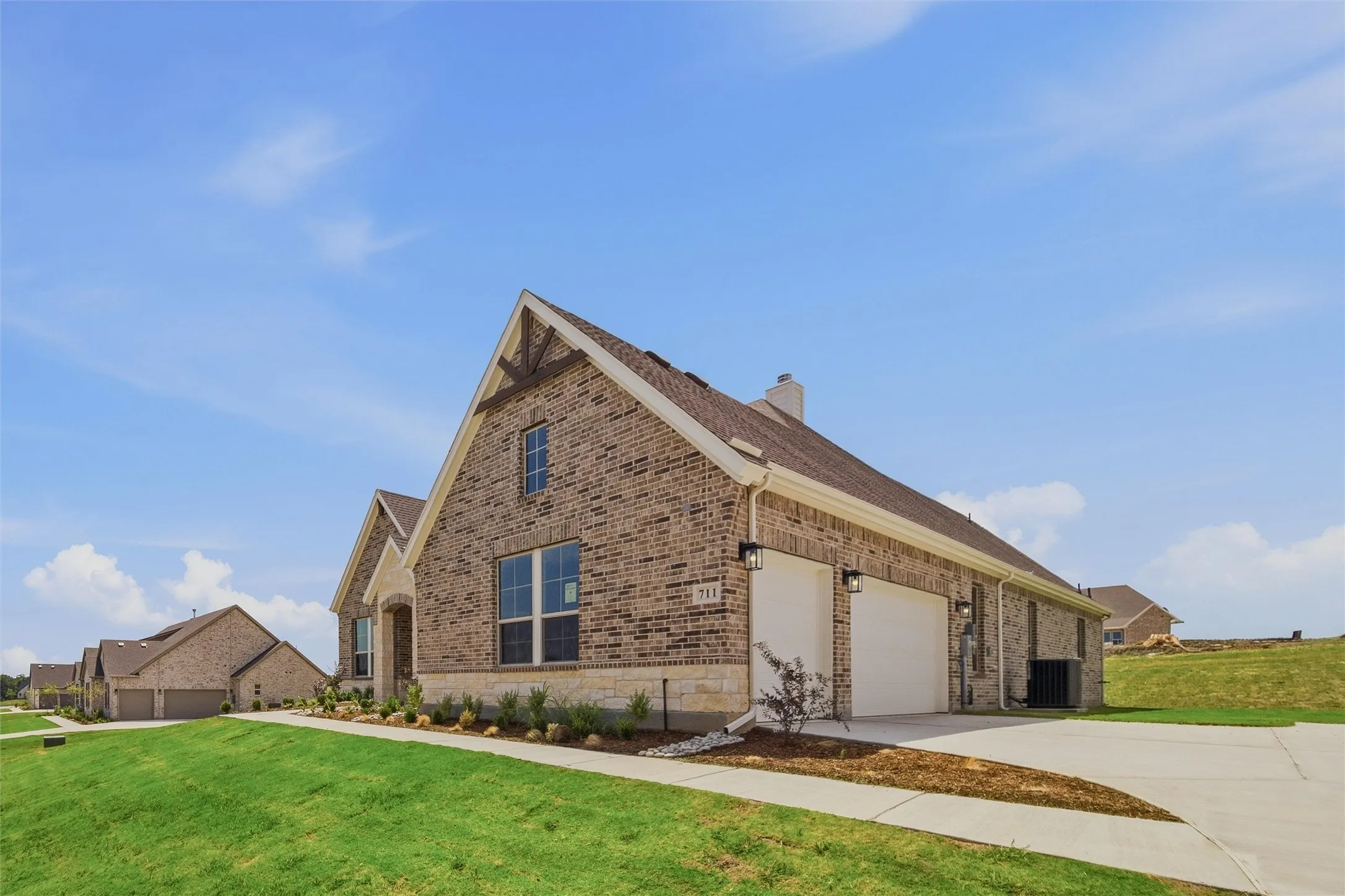 Modern stone residence featuring a steeply pitched roof with multiple gables, large multi-pane windows, and a covered front entry