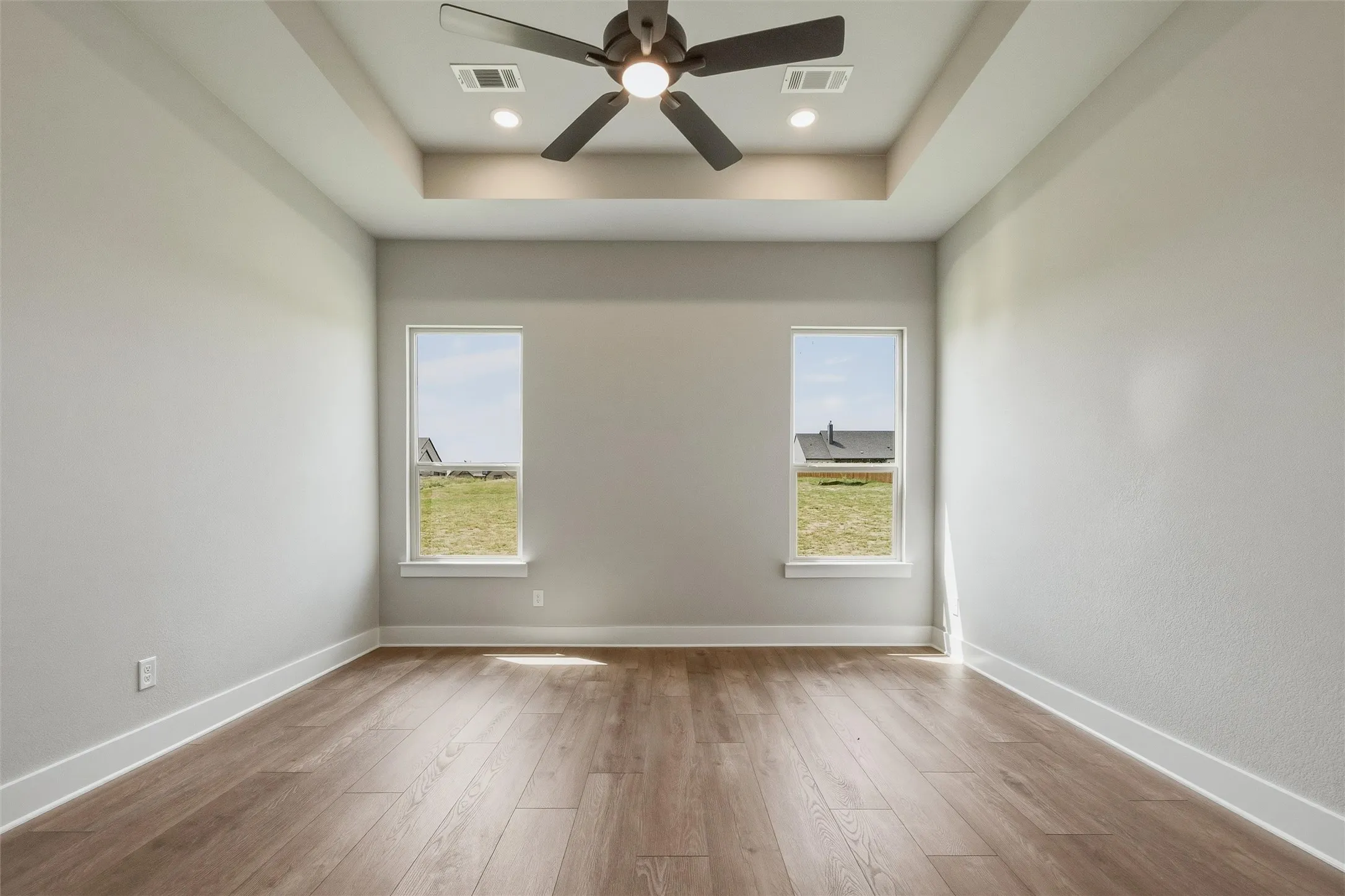 Tray ceiling with recessed lighting, wood-finish flooring, and a ceiling fan