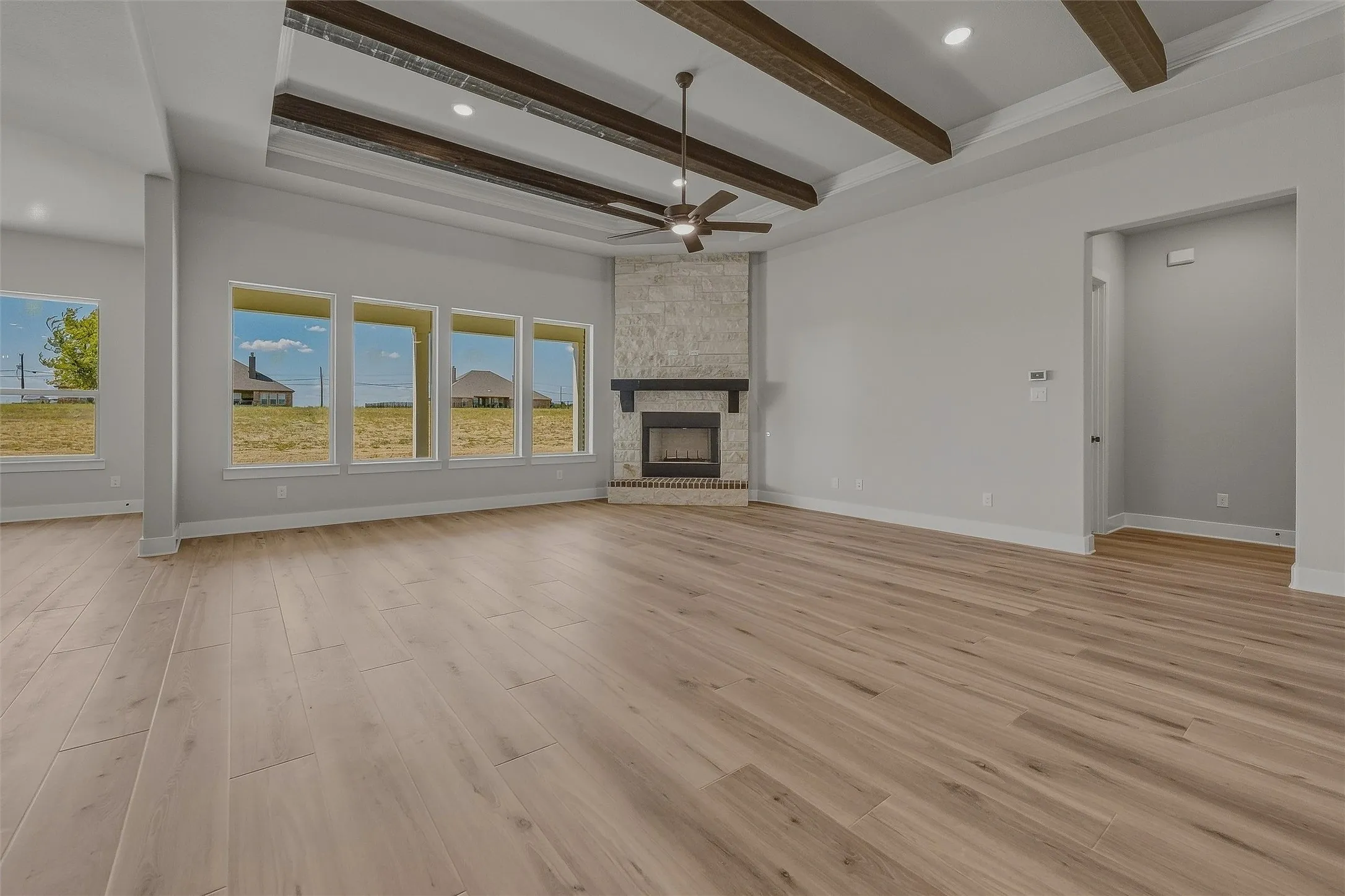 Spacious interior with wood-finish flooring, a stone-clad fireplace, and a wood-beam vaulted ceiling